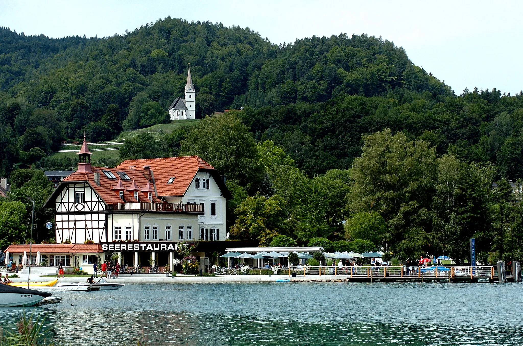 Photo showing: Restaurant Sille in the bay of Reifnitz on the Lake Woerth, behind above the subsidiary church Saint Anna, municipality Maria Woerth, district Klagenfurt-Land, Carinthia, Austria