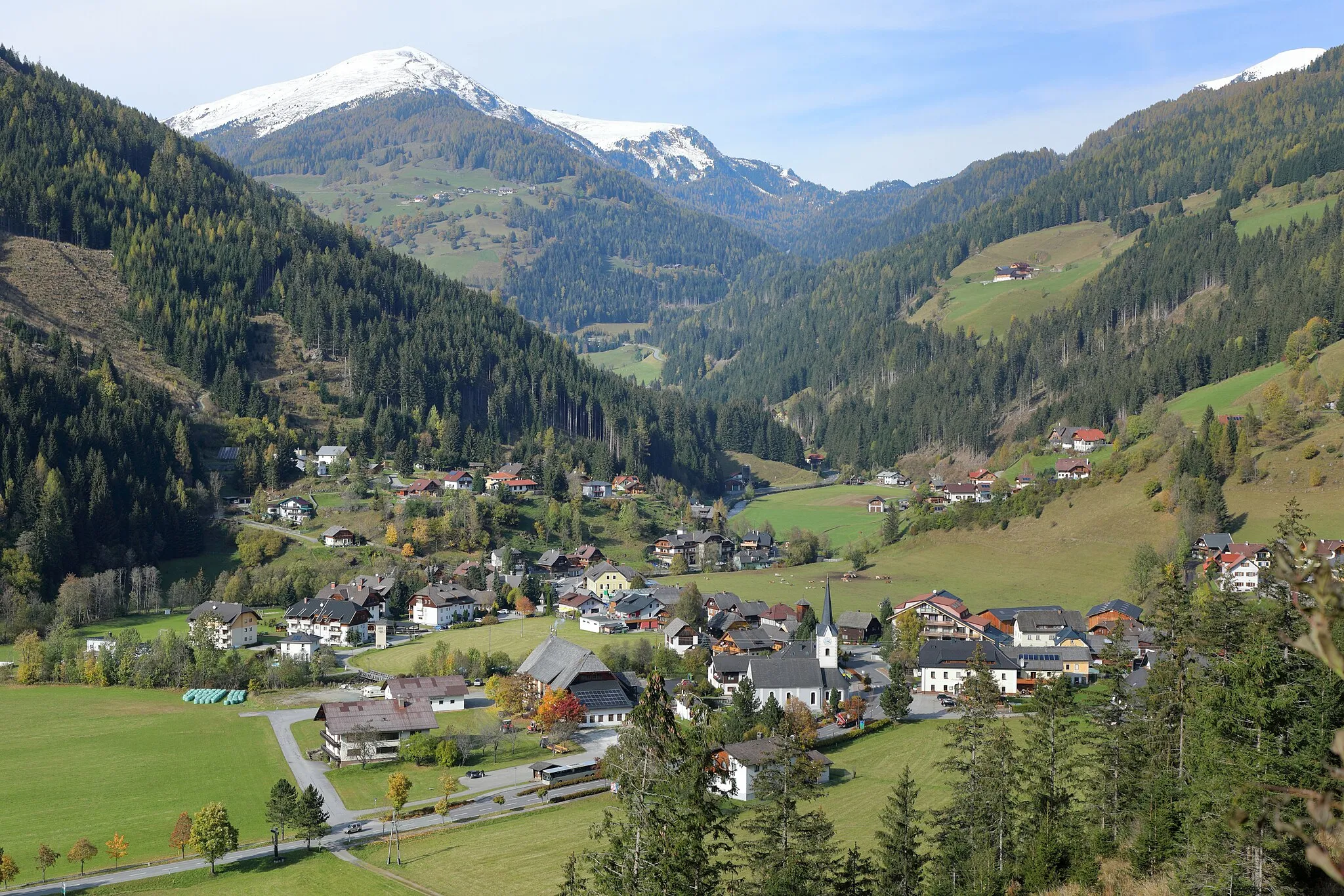 Photo showing: Blick von Südsüdost auf das Dorf „Ebene Reichenau“ in der Kärntner Gemeinde Reichenau und im Hintergrund die schneebedeckten Berge (von links nach rechts): Rinsennock (2334 m), Kornock (2193 m) und der Schoberriegel (2208 m) sowie die Turracher Höhe (1795 m) zwischen dem Kornock und Schoberriegel.