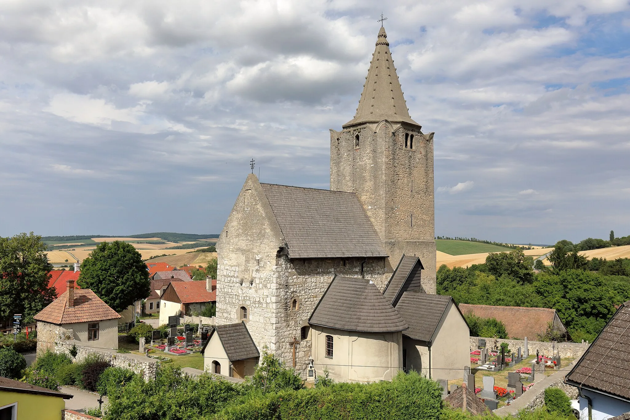 Photo showing: Südwestansicht der röm.-kath. Pfarrkirche hl. Veit in Michelstetten, ein Ortsteil der niederösterreichischen Marktgemeinde Asparn an der Zaya. Die spätromanische Wehrkirche mit frühgotischem Chorturm und eingezogener Rundapsis ist der älteste Kirchenbau im nordöstlichen Weinviertel. Sie ist von einem Friedhof umgeben, dessen Mauer teilweise frühmittelalterlich ist. Das Glockengeschoss des Turmes wurde im 16. Jahrhundert aufgesetzt und die eingeschossige Sakristei an der südlichen Chorturmwand wurde im Spätmittelalter errichtet. Die barocken und rund geschlossenen Kapellen mit Lisenengliederung an der Nord- und Südseite des Langhaus wurden 1752 angebaut.