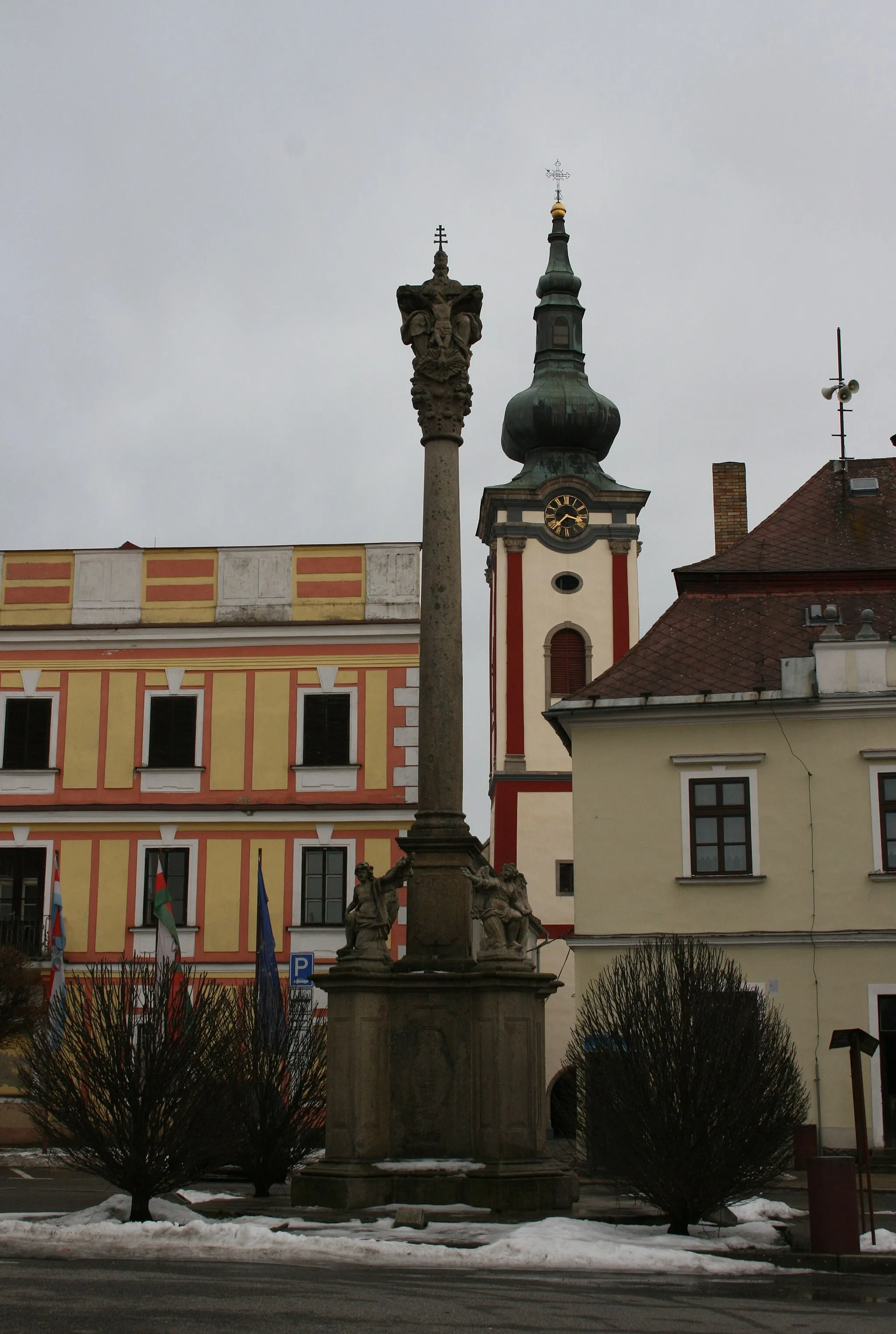 Photo showing: Plaque statue from 1676 with the statue of trinity and church of St. Peter and Paul in the Mírové square of Nová Bystřice, Jindřichův Hradec district, Czech Republic.