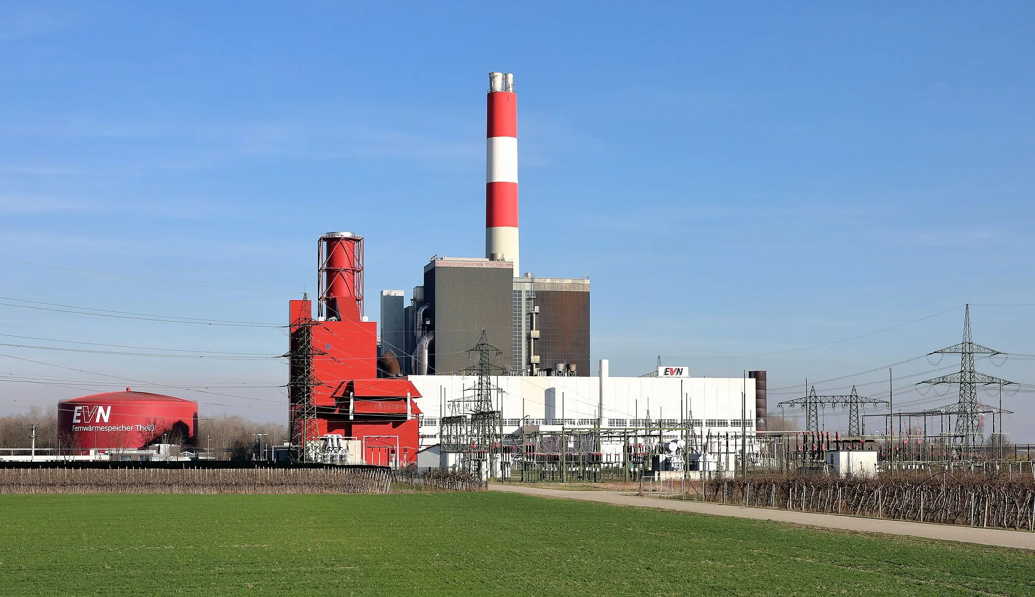 Photo showing: Nordwestansicht des Wärmekraftwerkes in Theiß, ein Ortsteil der niederösterreichischen Gemeinde Gedersdorf, und links der 50.000 m³-Fernwärmespeicher. Das Kraftwerk mit Schwarzstarteignung und einer Nennleistung von rund 800 Megawatt sowie einem 135m hohen Schornstein ist das größte, das der Energieversorger Niederösterreich (EVN AG) betreibt. Der Fernwärmespeicher links im Bild ist 30 Meter hoch, hat einen Durchmesser von 50 Metern und war ursprünglich ein Öltank. Bei der Inbetriebnahme am 11. Jänner 2008 war er der größte Fernwärmespeicher Europas.