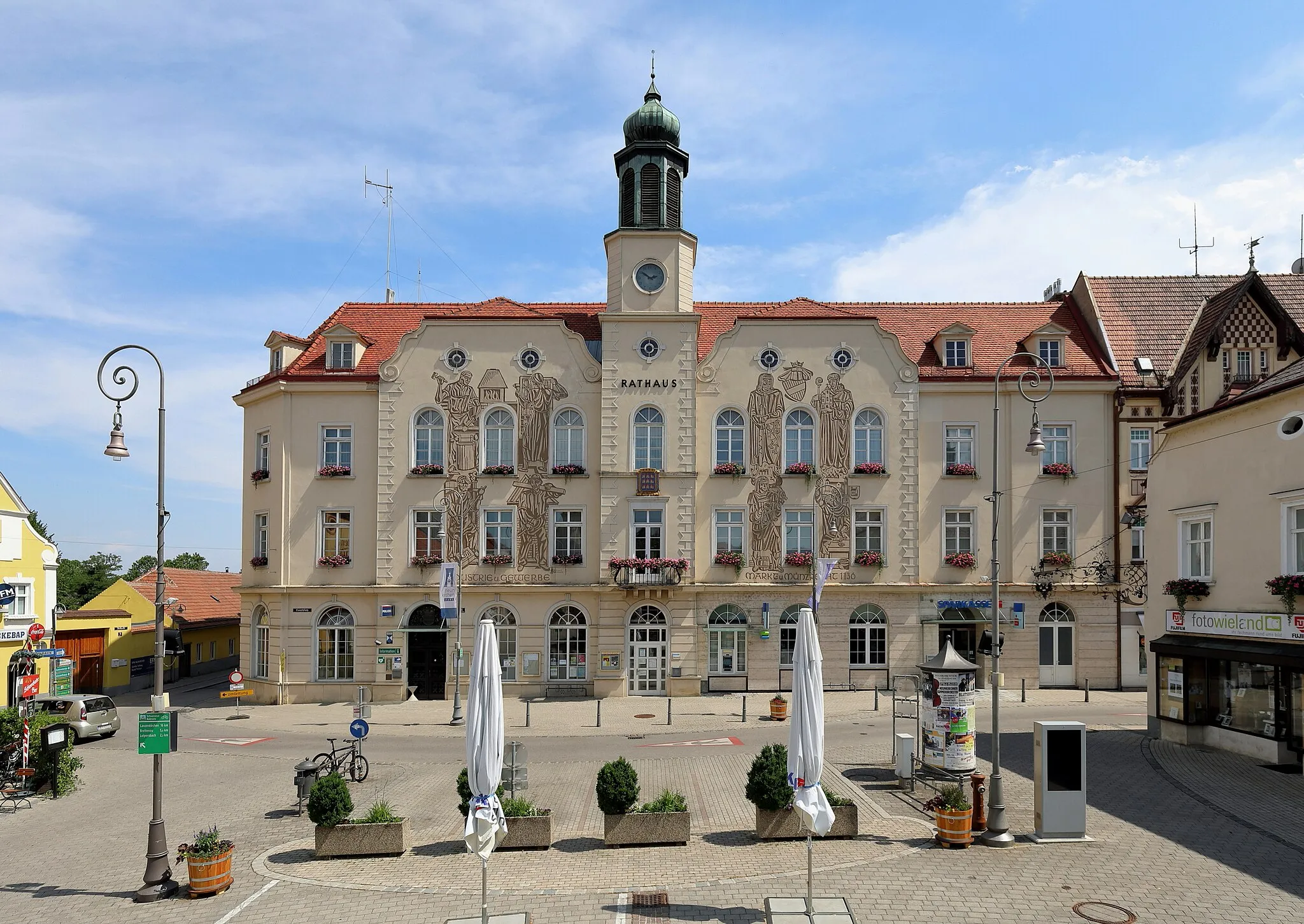 Photo showing: Nordwestansicht des Rathauses in der niederösterreichischen Stadtgemeinde Neunkirchen. Das Rathaus wurde von 1948 bis 1950 nach Plänen des Architekten Leo Kammel erbaut, nachdem kurz vor Ende des zweiten Weltkrieges das ursprüngliche Rathaus durch einen Großbrand zerstört wurde. Die Sgraffiti an der Rathausfassade sind ein Gemeinschaftswerk der Neunkirchner Künstler Karl Steiner und Fritz Weninger.