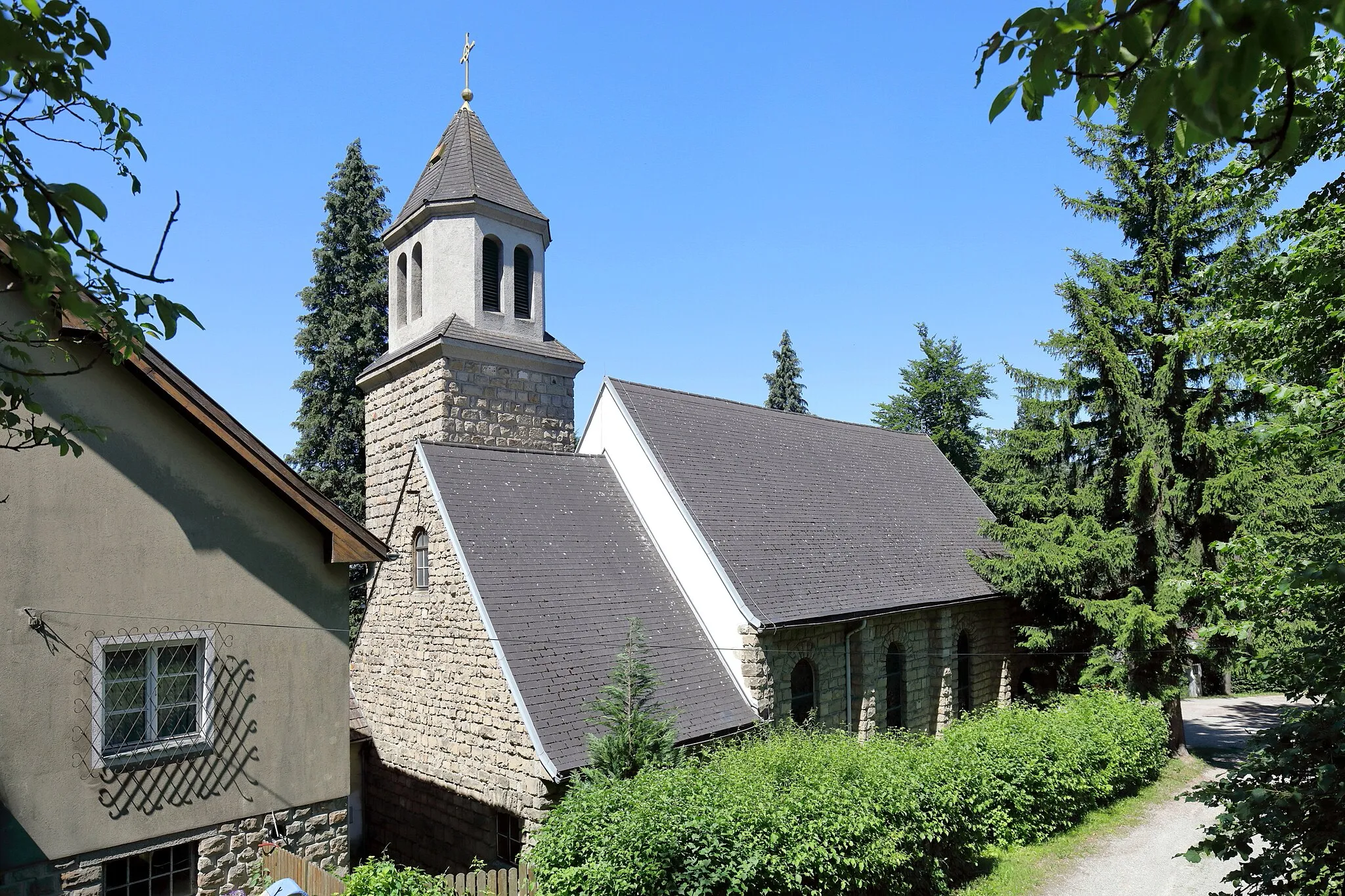 Photo showing: Ostansicht der Dollfuß-Gedächtniskirche hl. Theresia vom Kinde Jesu in Rekawinkel, ein Ortsteil der niederösterreichischen Stadtgemeinde Pressbaum. Der freistehende Kleinkirchenbau mit eingezogenem niedrigerem Chor und südlichem Chorwinkelturm wurde ab Herbst 1933 errichtet und am 20. Oktober 1935 von Kardinal Theodor Innitzer geweiht. 1951 erfolgte die Erhöhung des Turmes und chorseitig der Pfarrhof errichtet. 1952 wurde Rekawinkel eine eigenständige Pfarre.