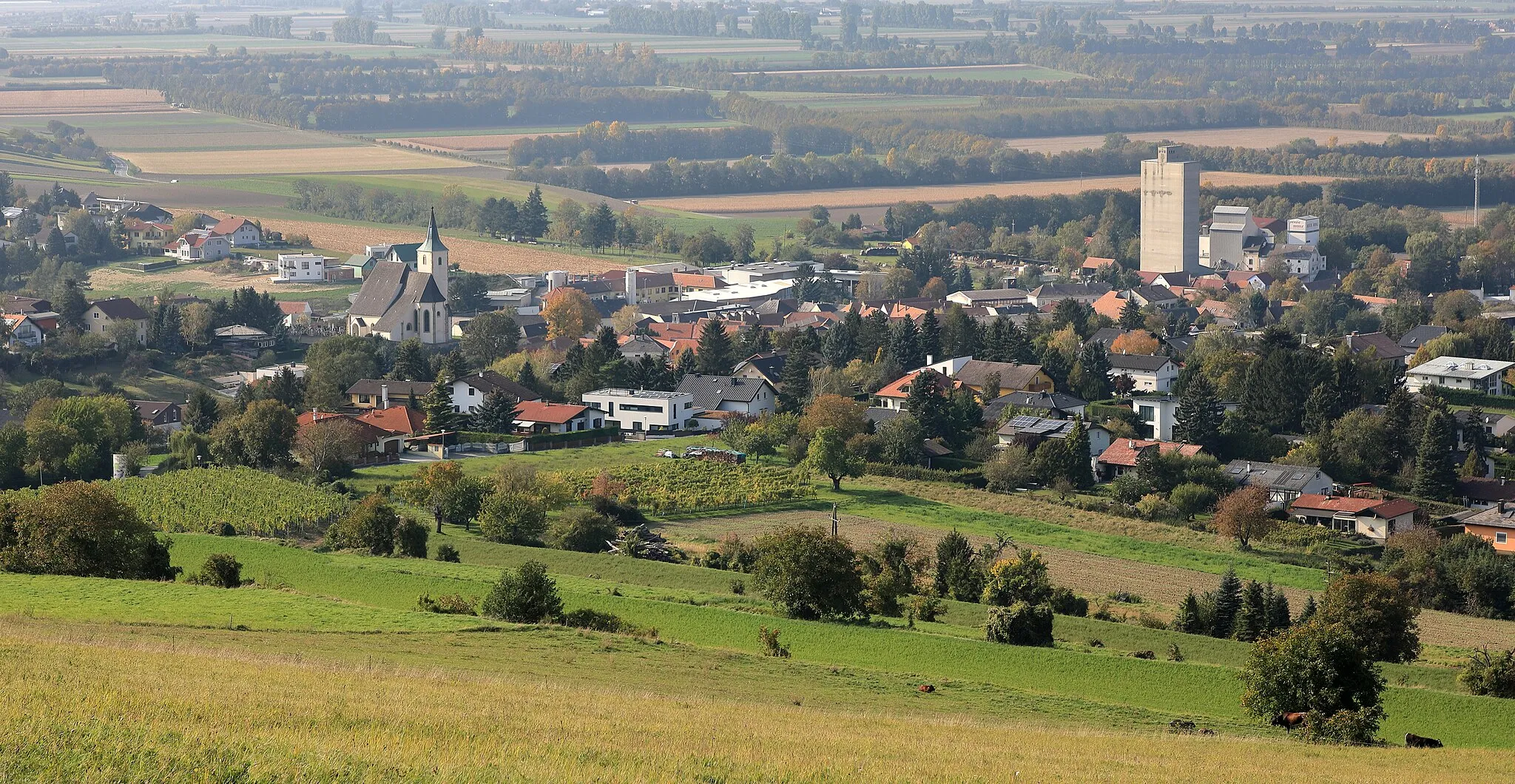 Photo showing: Ostsüdostansicht des Ortskernes der niederösterreichischen Marktgemeinde Tulbing mit der Pfarrkirche links im Bild und rechts dem markanten Getreidespeicher der Herzig-Mühle.