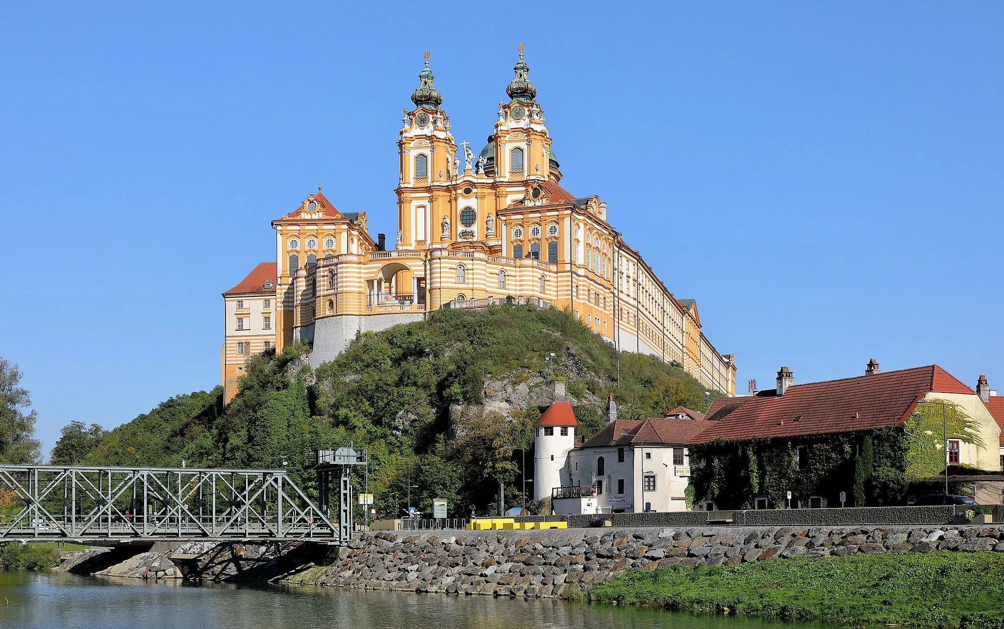 Photo showing: Westsüdwestansicht des 1089 gegründeten Benediktinerstiftes in der niederösterreichischen Stadtgemeinde Melk und im Vordergrund der Kramerturm an der Ecke Nibelungenlände/Kremser Straße sowie die denkmalgeschützte Stahlhubbrücke über den Donauarm. Die Stiftsanlage wurde in der 1. Hälfte des 18. Jahrhundert grundlegend umgebaut sowie erweitert und erhielt dabei im Wesentlichen ihr heutiges Erscheinungsbild.