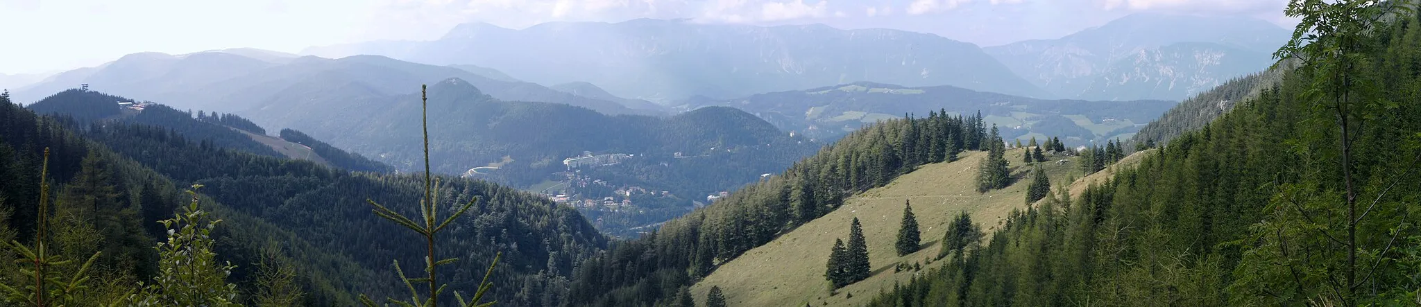Photo showing: Panoramic view of Rax (in the middle of upper part of image) and Schneeberg (right side) mountains from the slopes of Dürrriegel, with Hirschenkogel and its observation tower near the left edge and Semmering (Lower Austria) down in the valley (image centre).