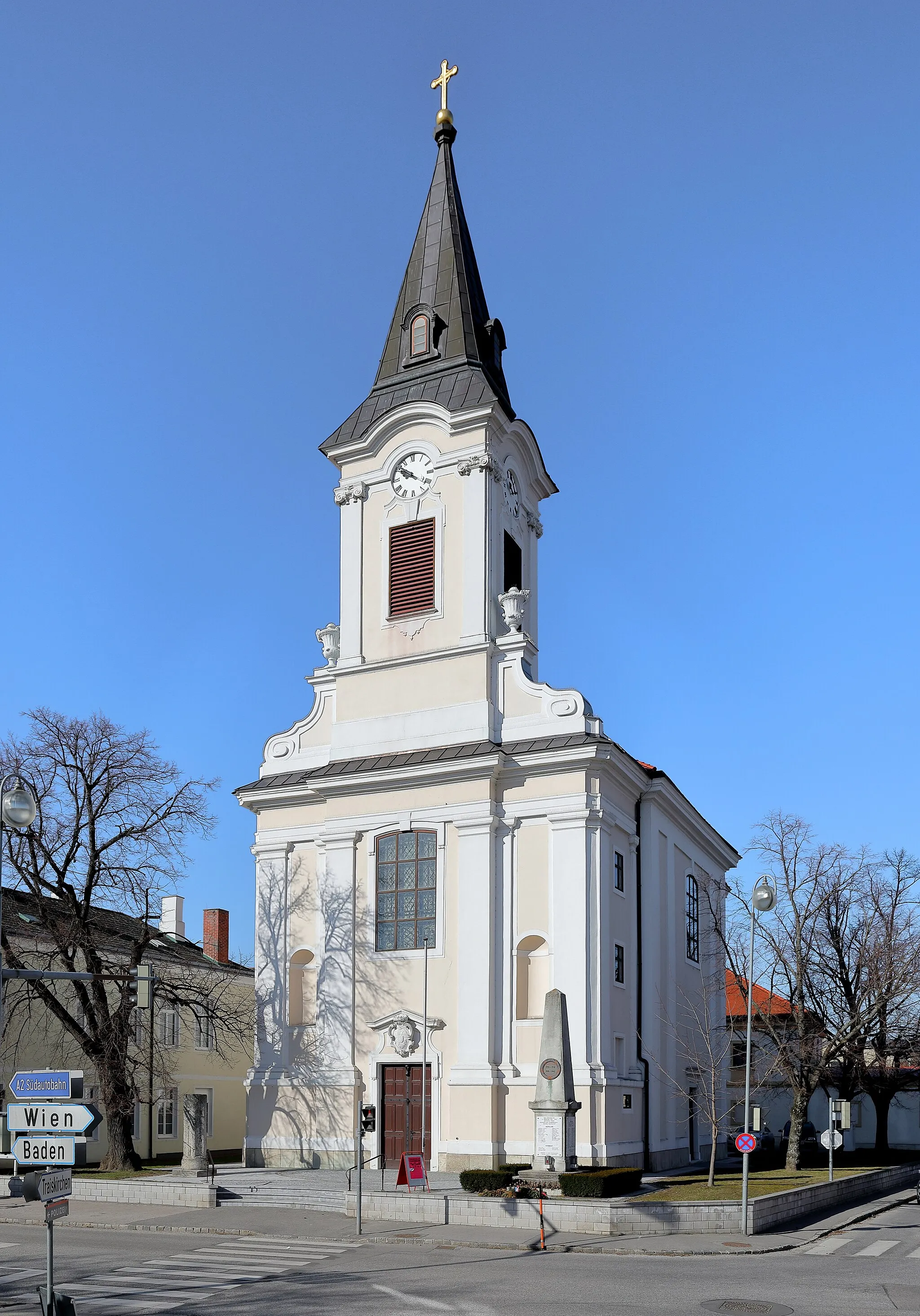 Photo showing: Ostansicht der röm.-kath. Pfarrkirche hl. Wolfgang in Tribuswinkel, ein Ortsteil der niederösterreichischen Stadtgemeinde Traiskirchen. Nachdem die Vorgängerkirche durch einen Brand zerstört wurde, erfolgte 1732 ein Neubau in Form einer barocken Saalkirche nach Plänen des Hofarchitekten Anton Marinelli. Bei einem neuerlichen Brand 1877 wurde der barocke Turmhelm durch einen Pyramidenhelm ersetzt.