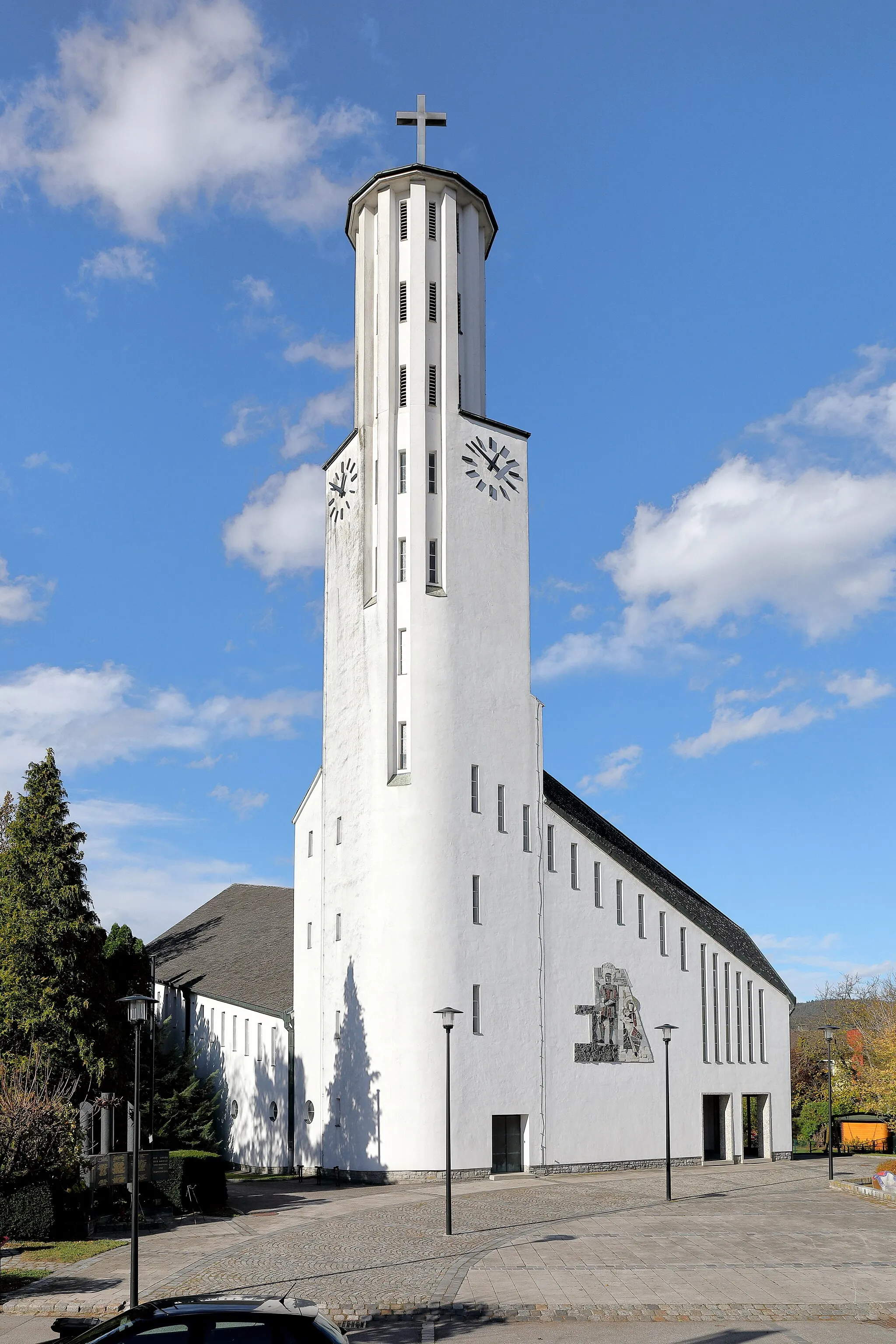 Photo showing: Südostansicht der röm.-kath. Pfarrkirche Zur Hl. Familie in der niederösterreichischen Marktgemeinde Prinzersdorf. Der expressionistische Bau in Skelettbauweise mit einem 36 Meter hohen, beherrschendem Fassadenturm sowie an- und absteigend konstruierten Dächern, stellt das „Schiff Petri“ dar und hat rund 400 Sitzplätze. Er wurde ab 1961 nach Plänen von Julius Bergmann erbaut und am 10. Juli 1966 vom St. Pöltner Bischof Franz Zak geweiht. Im gleichen Jahr wurde der Sitz der Pfarre von Gerersdorf nach Prinzersdorf verlegt und der Name der Pfarre in „Gerersdorf-Prinzersdorf“ umgewandelt. Seither handelt es sich faktisch um eine Doppelpfarre. Das monumentale Mosaik der Heiligen Familie an der Ostfassade ist ein Werk von Hermann Bauch und wurde 1968 geweiht.