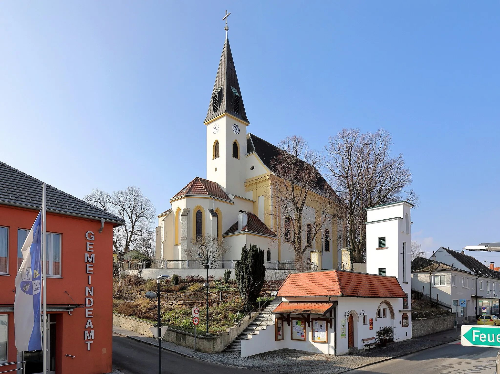 Photo showing: Das Ortszentrum der niederösterreichischen Marktgemeinde Auersthal. Im Zentrum des Bildes die in erhöhter Lage errichtete röm.-kath. Pfarrkirche hl. Nikolaus. Ganz links das Gemeindeamt und unterhalb der Kirche das ehemalige Zeughaus der Feuerwehr. Dieses wurde 1965 anstelle eines Vorgängerbaues errichtet und wird (2018) nach Adaptierung als Weinladen genutzt.