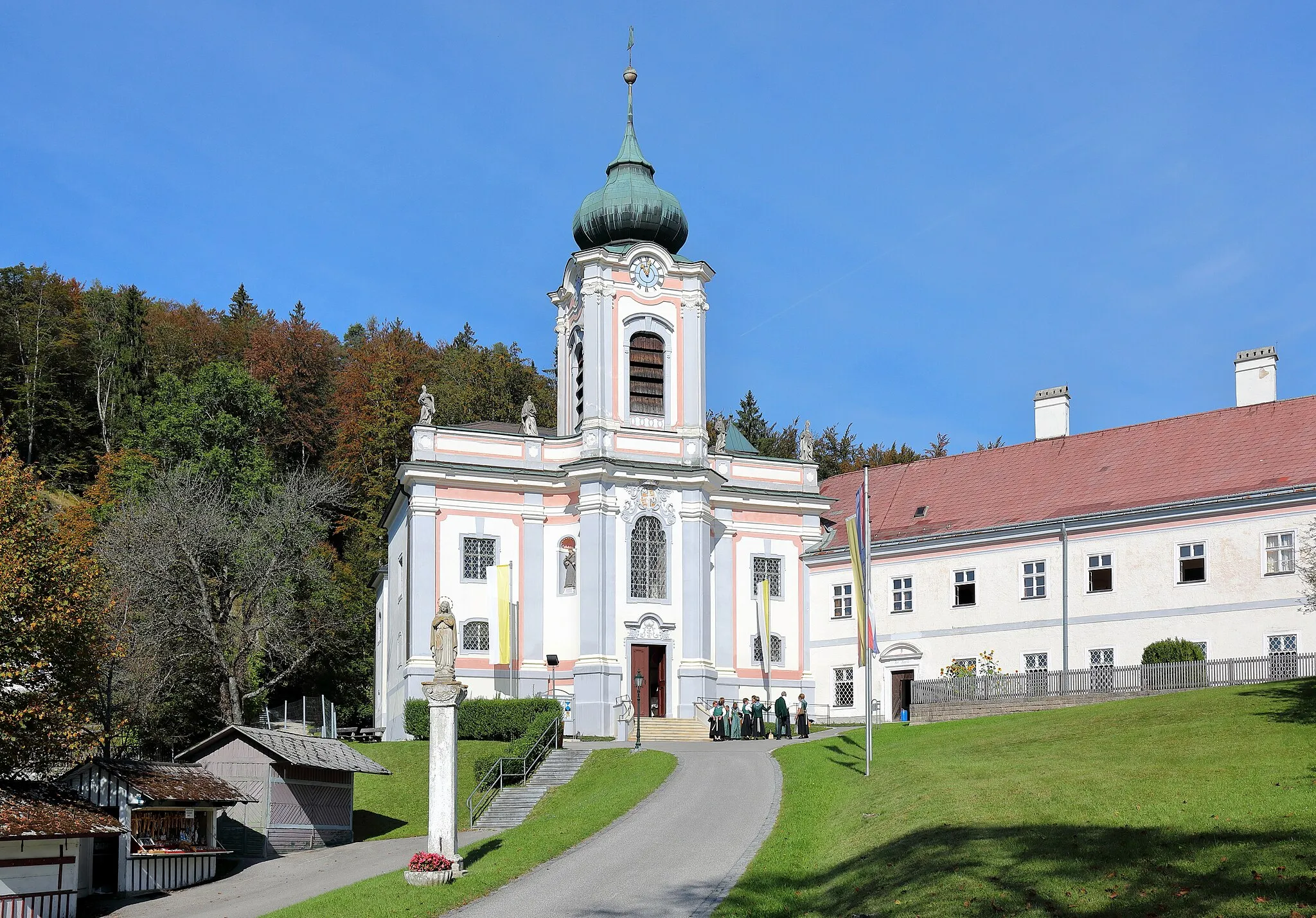 Photo showing: Der Weiler und Wallfahrtsort Mariahilfberg in der niederösterreichischen Marktgemeinde Gutenstein. In der Bildmitte die Kloster- und Wallfahrtskirche Hilfreiche Jungfrau Maria. Diese Kirche wurde anstelle einer 1705 abgebrannten Kirche in vergrößerter Form von 1710 bis 1721 neu errichtet. Rechts das im stumpfen Winkel angebaute Servitenkloster, das 1672 von Johann Balthasar II. von Hoyos (1626–1681) gestiftet wurde. Links im Bild Devotionalien-Verkaufsstände und eine Maria-Immaculata-Statue aus dem 19. Jahrhundert auf einem Schaft mit Kapitell um 1700.