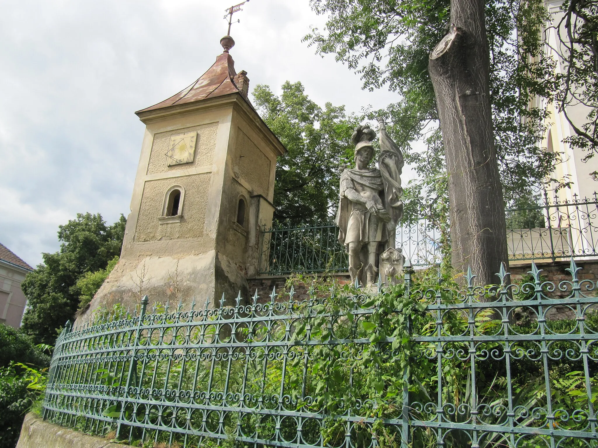 Photo showing: Dyjákovice in Znojmo District, Czech Republic. Turret in the wall of the church with a sundial and statue of St. Florian.