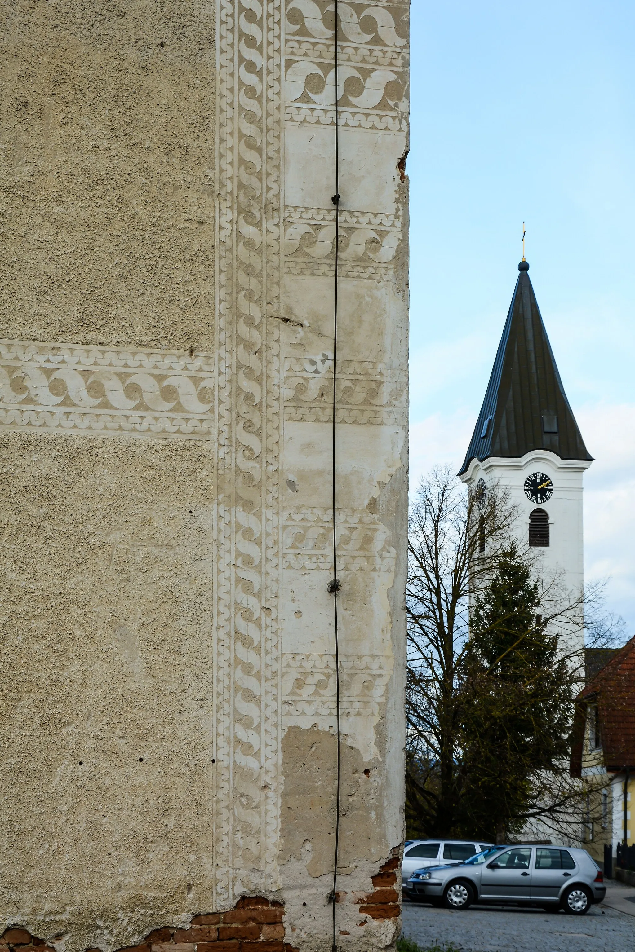 Photo showing: The church spire of the cath. parish church in Berg (Ansfelden) with the corner of the farm house "Zehetner" which is decorated with sgraffiti.