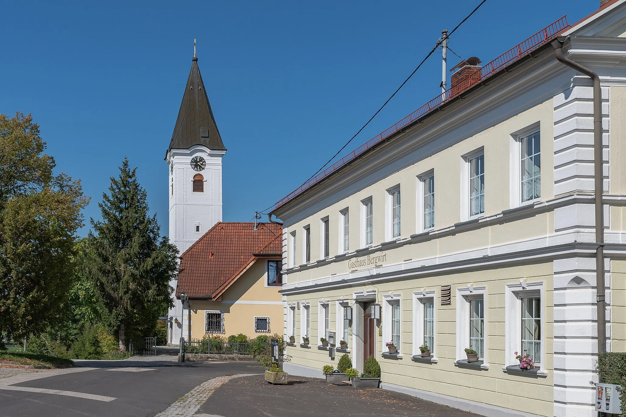 Photo showing: The catholic parish church of Berg an der Krems is dedicated to St. Vitus. Between 1853 and 1902 the sacristans house was a school and domicile of the teacher.