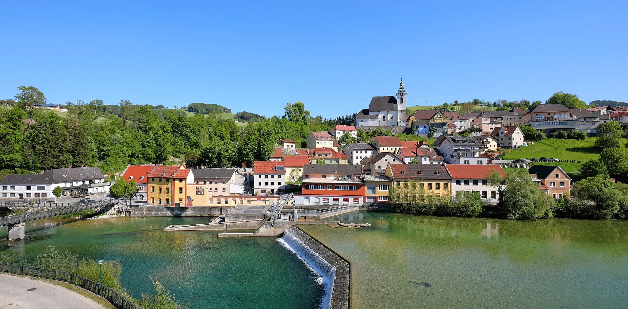 Photo showing: Nordwestansicht der oberösterreichischen Gemeinde Steinbach an der Steyr mit dem Kraftwerk Steinbach im Vordergrund und im Hintergrund die in erhöhter Lage errichtete röm.-kath. Pfarrkirche hl. Bartholomäus. Das Kraftwerk wurde ursprünglich 1911 gebaut. Im Jahr 2001/02 wurde es neu erbaut und liefert bei einer Fallhöhe von 2,76 Meter durchschnittlich jährlich rd. 5,3 Mio. kWh.