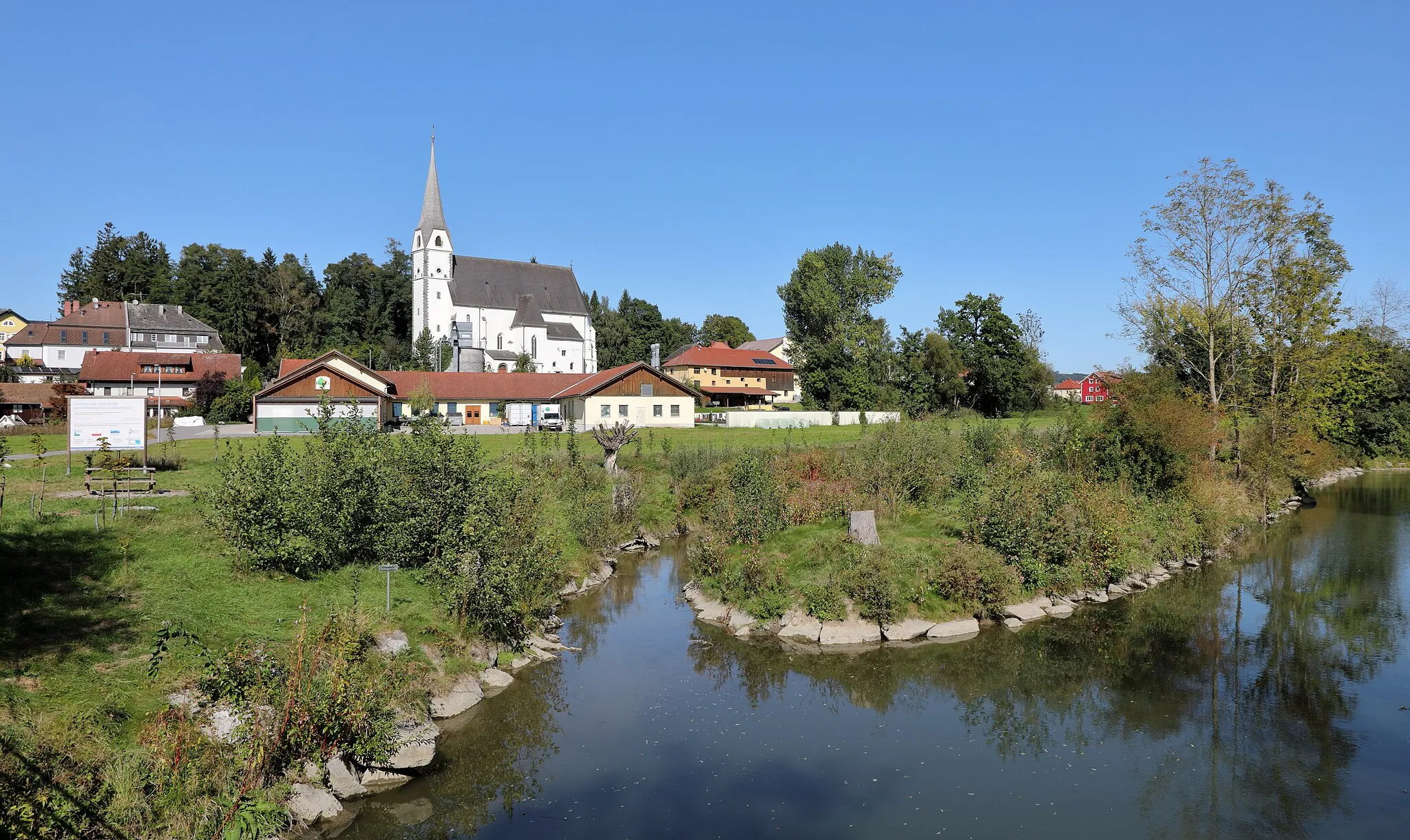 Photo showing: Teil der oberösterreichischen Marktgemeinde Taufkirchen an der Pram mit der Pram im Vordergrund und der röm.-kath. Pfarrkirche Mariä Verkündigung im Hintergrund. Die Pram wurde an dieser Stelle mit einen Nebenarm 2016/17 um 250.000,- Euro renaturiert.