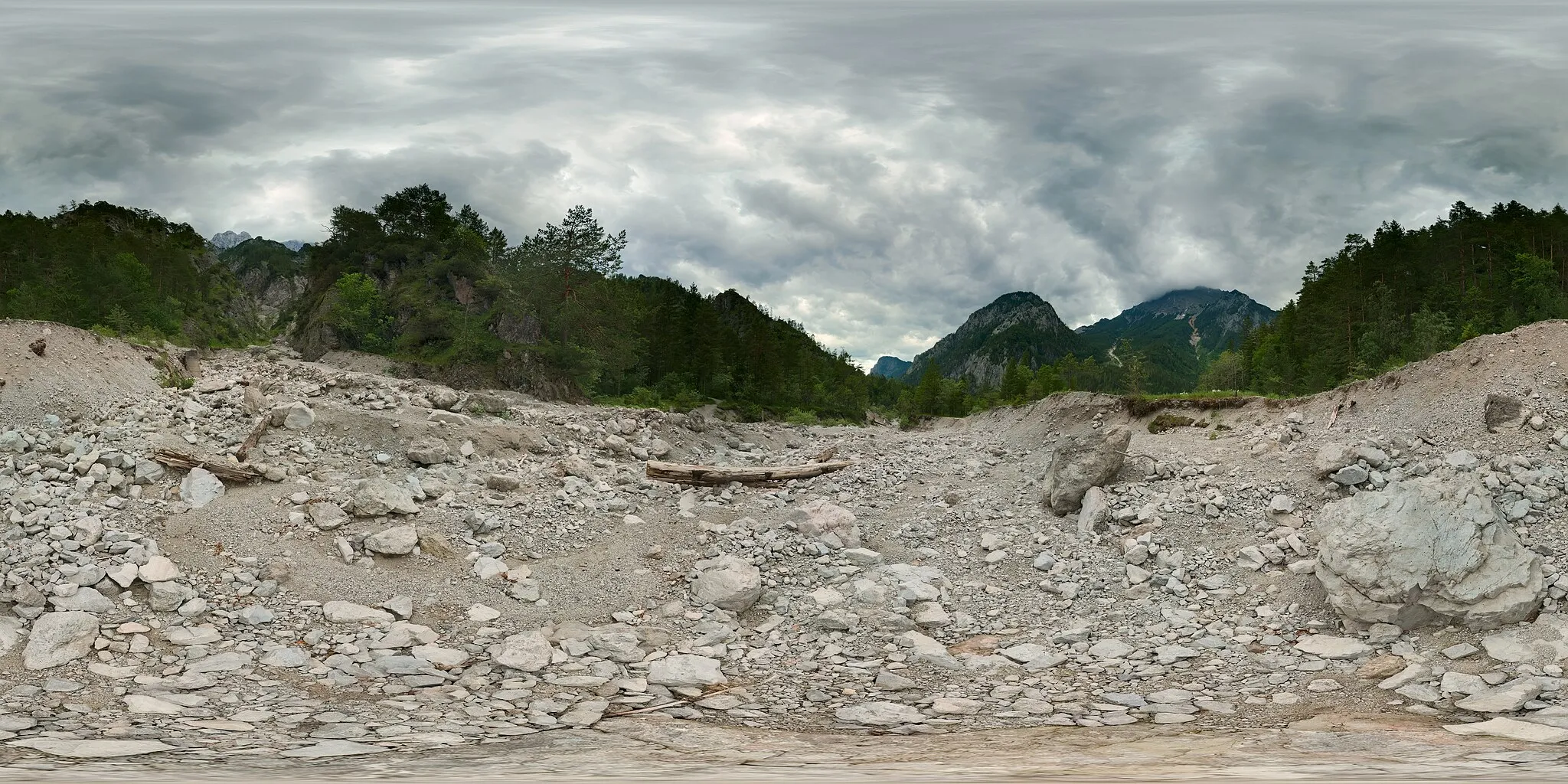 Photo showing: This is a spherical panoramic taken in a dry canyon near the Haindlkar (and joining the Haindlkarbach downstream).  This is the bed of a stream which is dry most of the time, but will carry water on occasion of heavy rains.  The erosion and flow of driftwood and stones downstream is evident.  This panorama was created from two layers of different exposure, with 15 images each (so 30 individual shots on total).