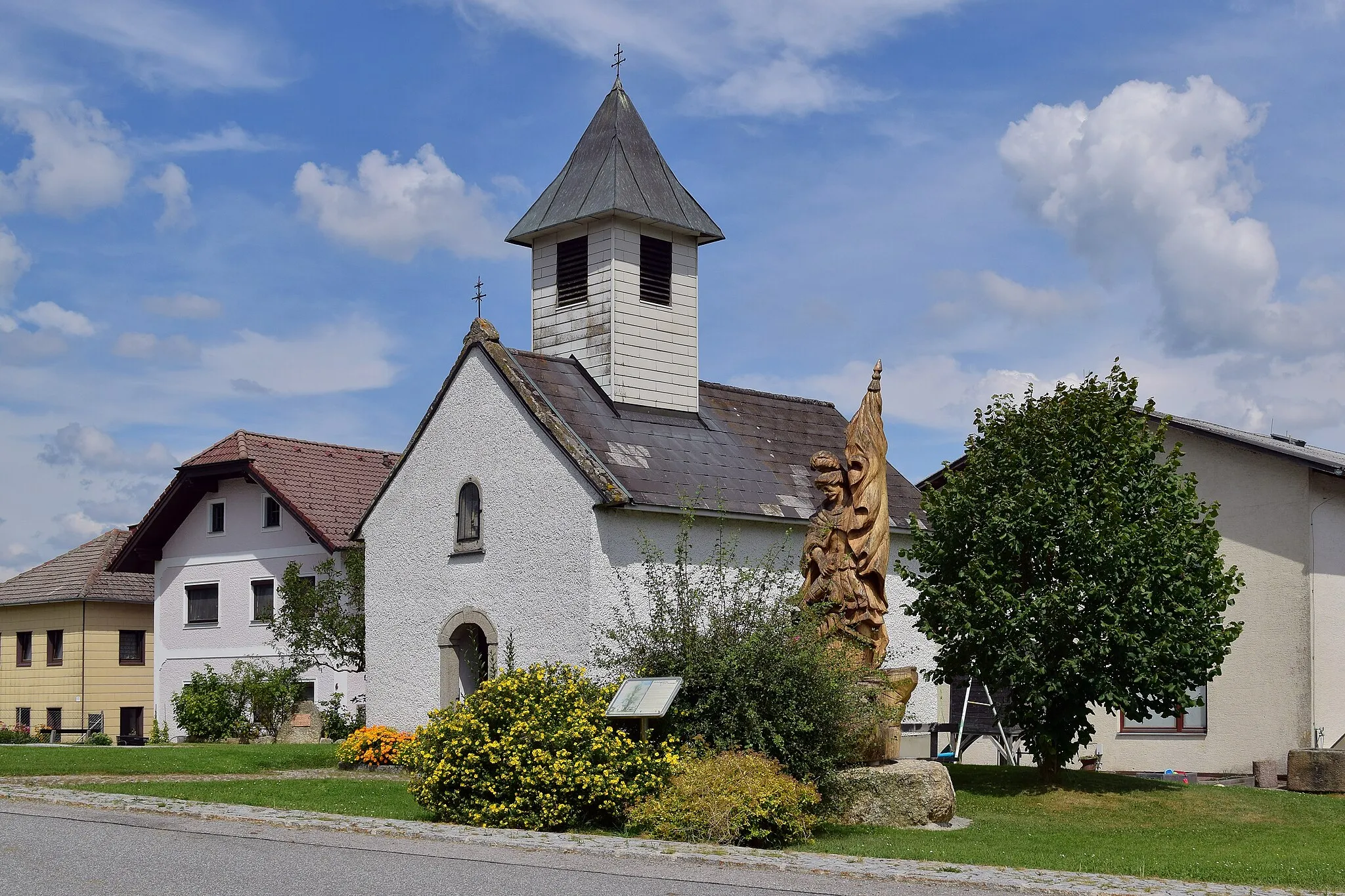 Photo showing: Dorfkapelle Langfirling mit geschnitzter Florian-Statue. Die Statue ist nicht mehr aus dem ehemaligen Naturdenkmal Dorflinde, denn deren Stamm war morsch, weshalb die Statue 2018 durch eine Neuanfertigung ersetzt wurde.[1]