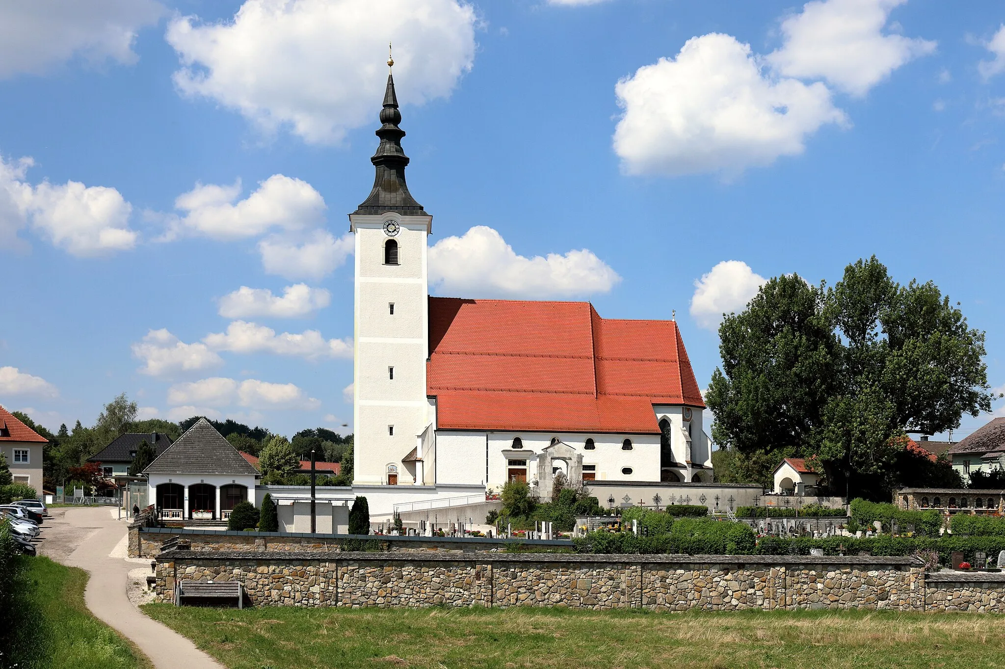 Photo showing: Südansicht der von einem Friedhof umgebenen röm.-kath. Pfarrkirche Hl. Jakobus der Ältere in der oberösterreichischen Marktgemeinde Seewalchen am Attersee und rechts die unter Naturschutz stehenden Friedhofsesche. Die gotische Kirche wurde Mitte des 15. Jahrhunderts errichtet und 1476 geweiht. Im 19. Jahrhundert fand eine Erweiterung des südseitigen Anbaus statt und der Turm wurde ebenfalls neu gestaltet. Von 1998 bis 2001 wurde die Pfarrkirche umgebaut, komplett renoviert und erweitert, dabei würde unter anderem nordseitig sozusagen ein linkes Seitenschiff errichtet.