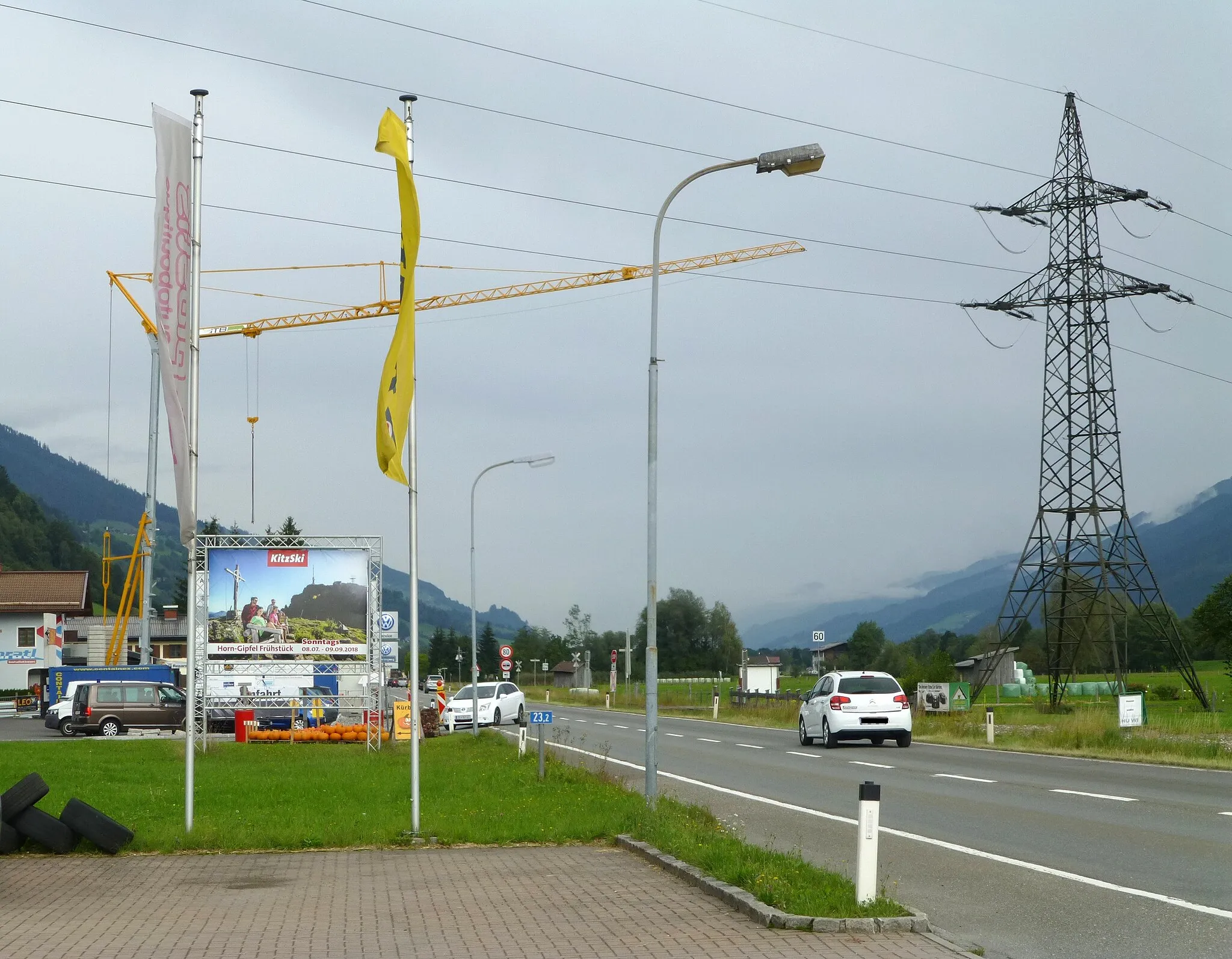 Photo showing: Modernity in Mittersill: power line, lamps, flags, pub, but also a Kurbiss selling.
