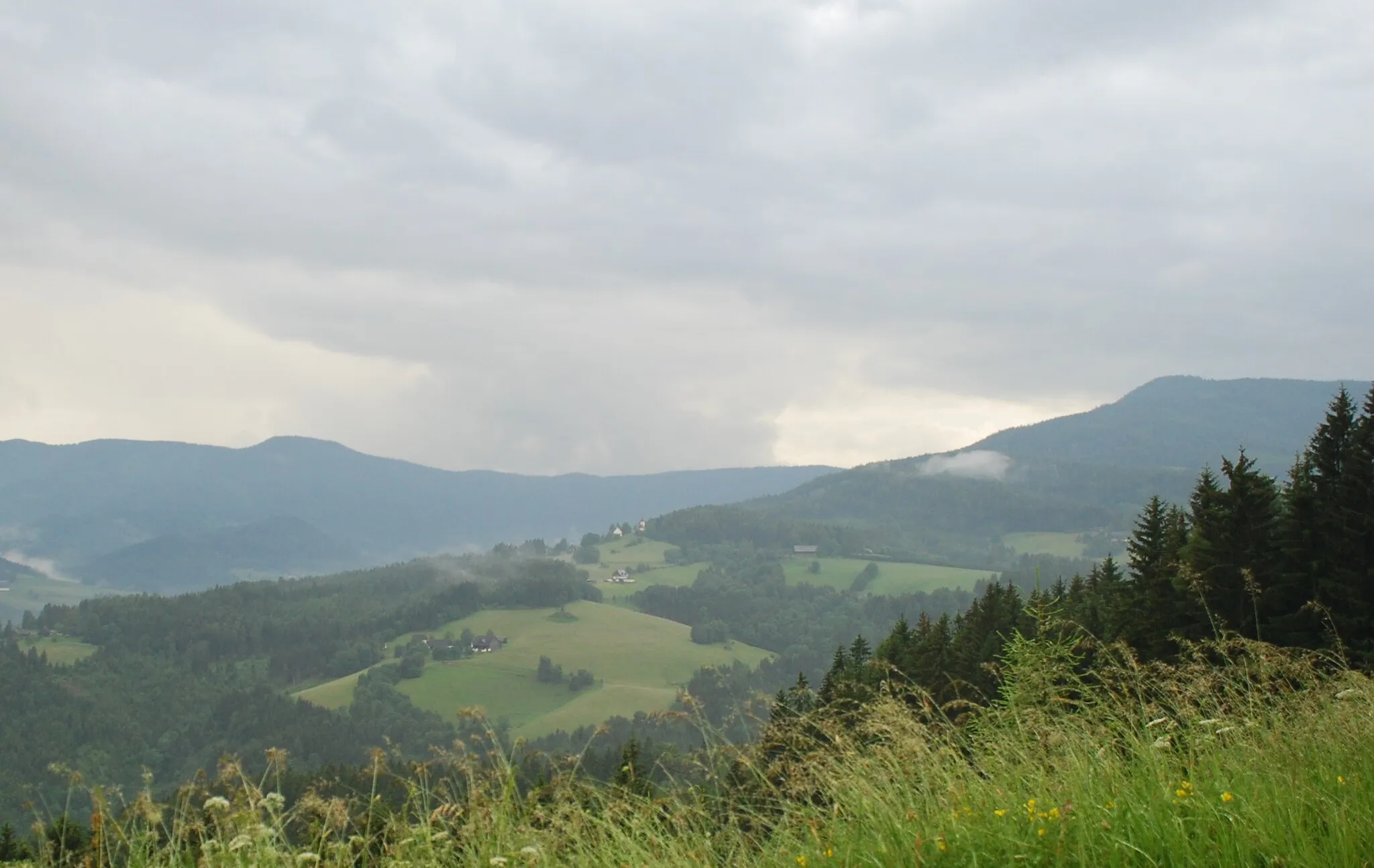 Photo showing: St. Oswald in Freiland auf dem Höhenzug des Schwarzkogels (Wolfsrücken), rechts Schwarzkogel-Gipfelkuppe. Im Tal dahinter (dunkel) Pöschlkogel, darüber Stoffkogel