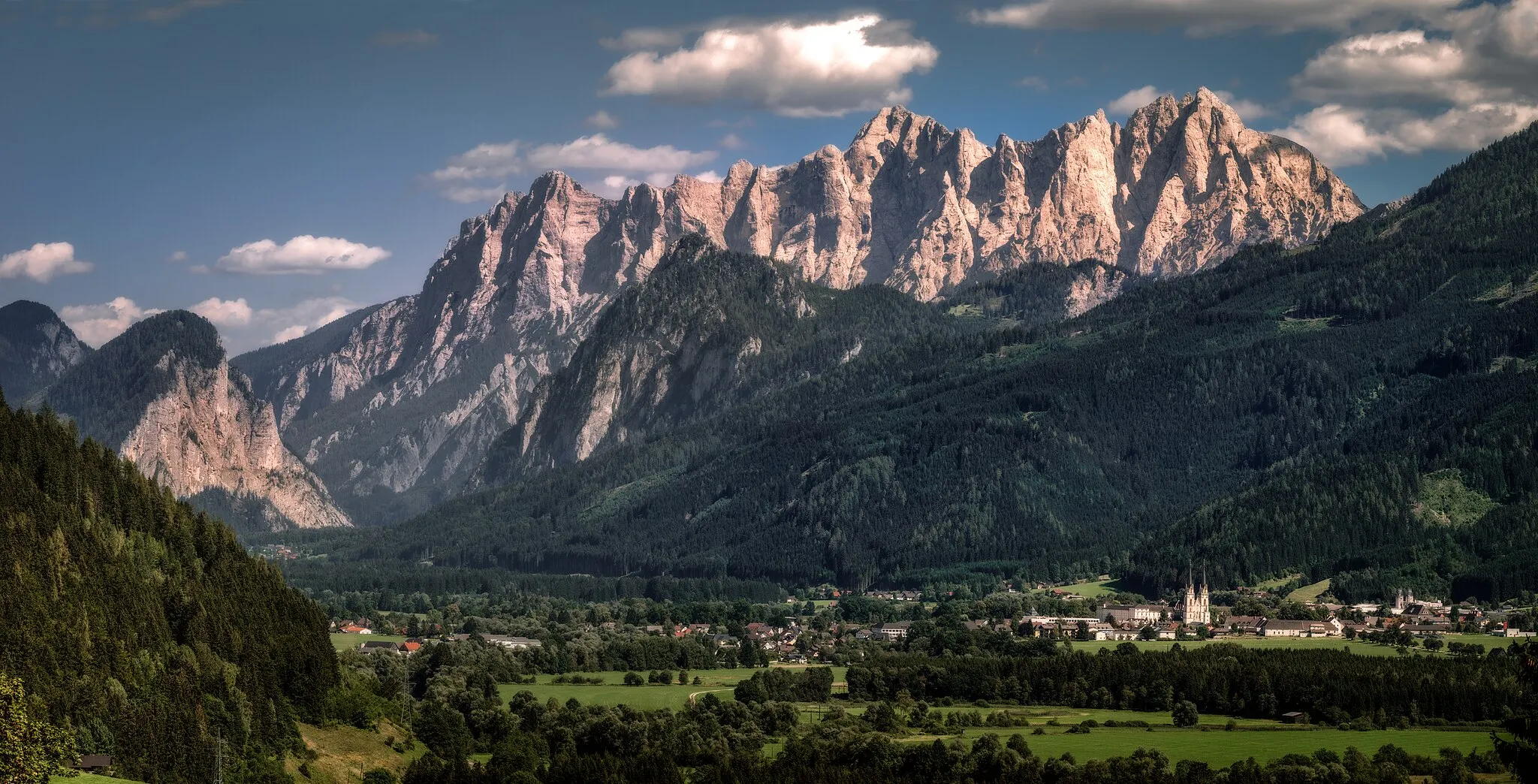 Photo showing: The Hochtor mountain range is situated south of the river Enns in Styria, Austria. Its peaks rise about 1800 meters above the valley. The Hochtor (in the center of the image) has a height of 2730 m and is the highest summit in the Gesäuse National Park.
The village in front of the mountains is Admont, famous for its historic monastery, founded in 1074. Here you can see the towers of the abbey church illuminated by the evening sun.

The original image is made available at high resolution (10000 pixels horizontally). Enjoy the details!