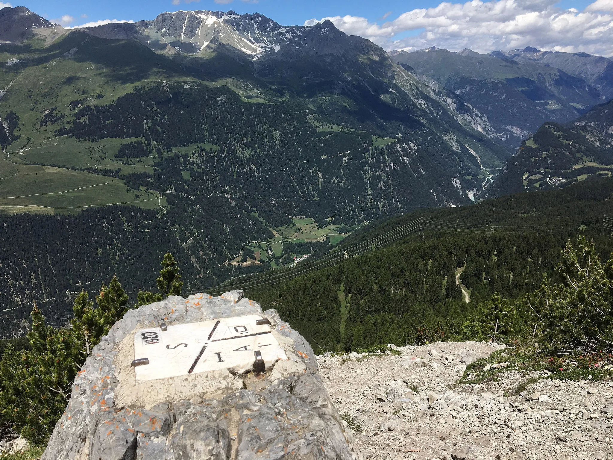 Photo showing: Top of the stone at the tripoint between Austria, Italy and Switzerland. With a view towards Martina (Valsot), Piz Mundin and Piz Alpetta. In the valley: Inn River.