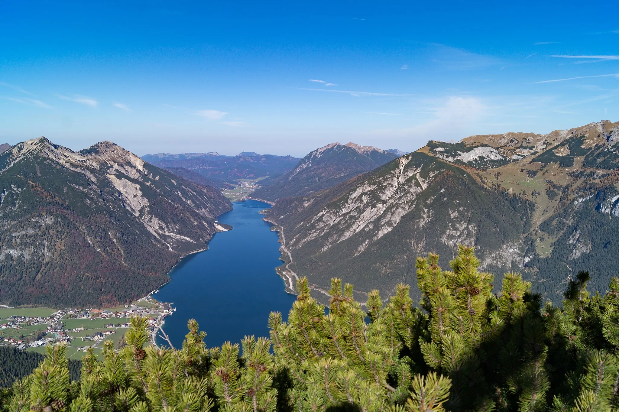 Photo showing: Blick vom Bärenkopf auf den Achensee. Links Pertisau und einige Berge des Karwendelgebirges (Seeberg- und Seekarspitze im Vorkarwendel), geradeaus nach Norden das Mangfallgebirge mit Ross- und Buchstein, bewaldete Kuppen und den höheren Hirschberg, rechts vom See Unnütze Berggipfel und das vorspringende Klobenjoch im Rofan oberhalb der Achenseestrasse und dem Kögljochsattel zwischen den Berggruppen. Dalfazalm und Steinernes Tor.