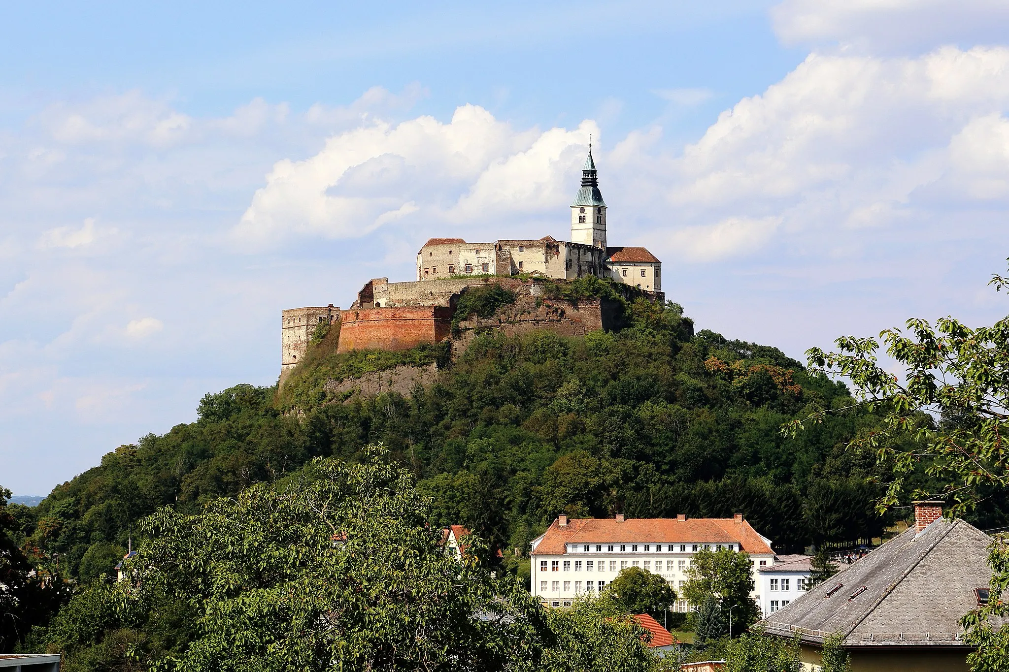 Photo showing: Südwestansicht der Burg Güssing in der burgenländischen Bezirkshauptstadt Güssing. Eine auf einem weithin sichtbar steilen Kegel vulkanischen Ursprungs Mitte des 12. Jahrhunderts errichtete Burg und damit älteste Burg Burgenlands. Im 16. und 17. Jahrhundert erfolgte der Ausbau zu einer Festung. Wegen der "Dachsteuer" gab man sie im 18. Jahrhundert dem Verfall preis. Seit 1957 wird eine Bestandssicherung betrieben und 1969 wurde das neue Burgmuseum eröffnet.