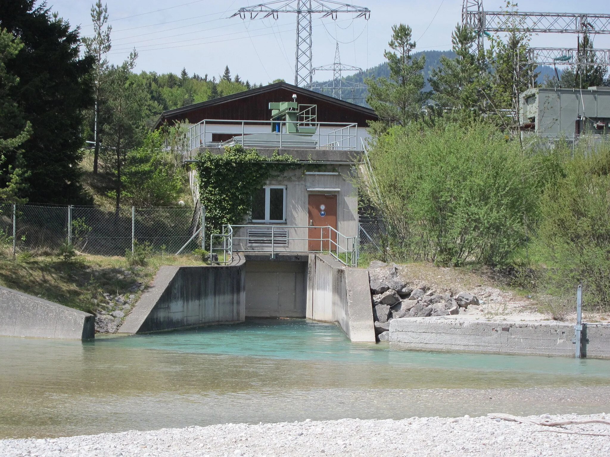 Photo showing: Isar-Stauwehr bei Krün, kleines Kraftwerk zur Nutzung des festgelegten Restwassers; rechts Teile des 220/110-kV-Umspannwerks Krün