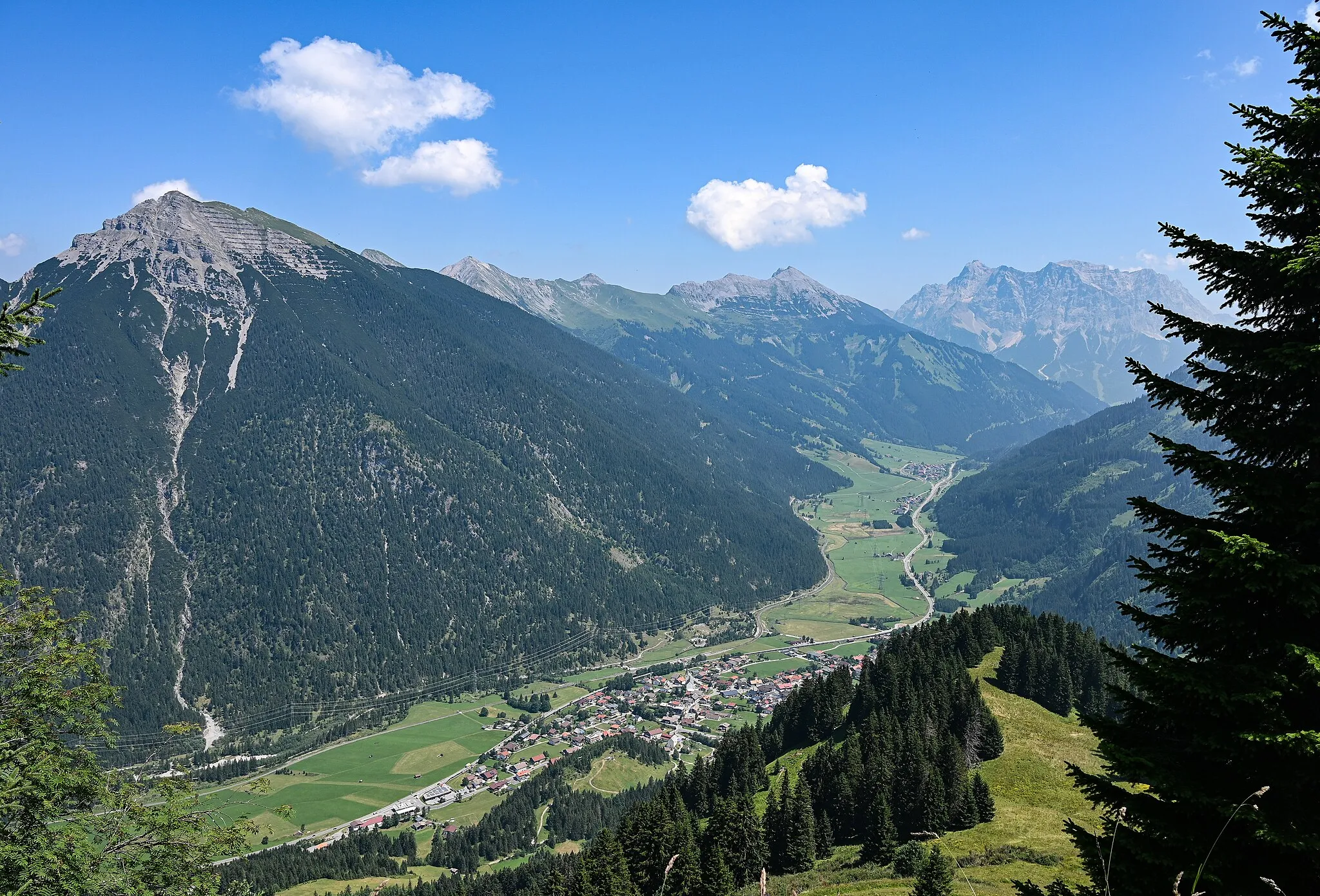 Photo showing: View from mountain Almkopf (1802m) over Kohlbergspitze, Daniel with Upsspitze and Zugspitze, valley with Bichlbach and street of the Tyrol Alps Fernpasstraße