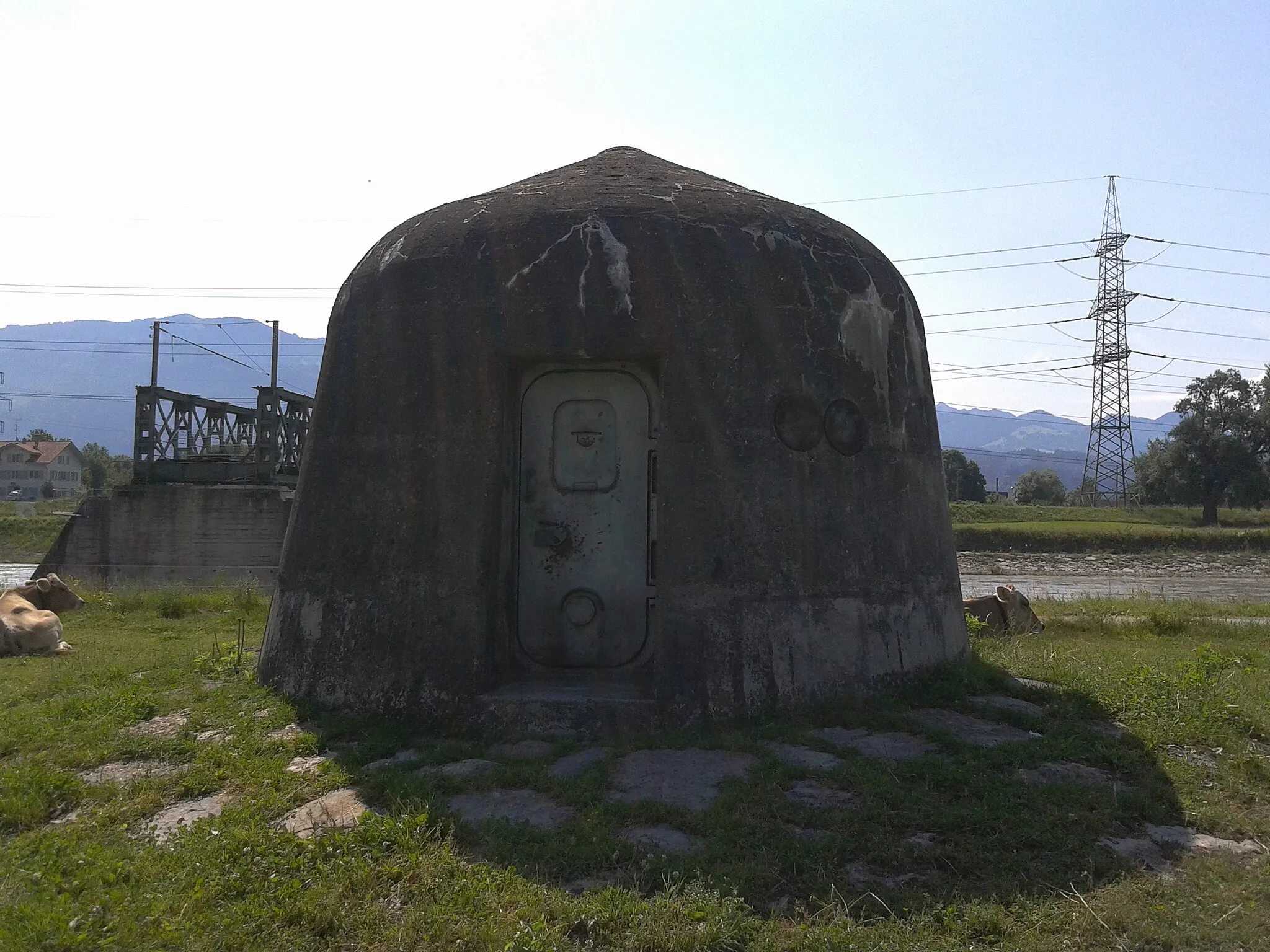 Photo showing: Grenzübergang Kriessern (CH) - Mäder (A). Bunker aus der Zeit WK-II zum Schutz der schweizerischen Grenze am Rhein - kuppelförmiger Leichtstand in Betonbunkerausführung mit Maschinengewehren (Schussrichtung längs des Rheines - nicht nach Österreich!). Fotografiert in der Schweiz im Überflutungsgebiet des Rheins mit Blickrichtung nach Österreich.