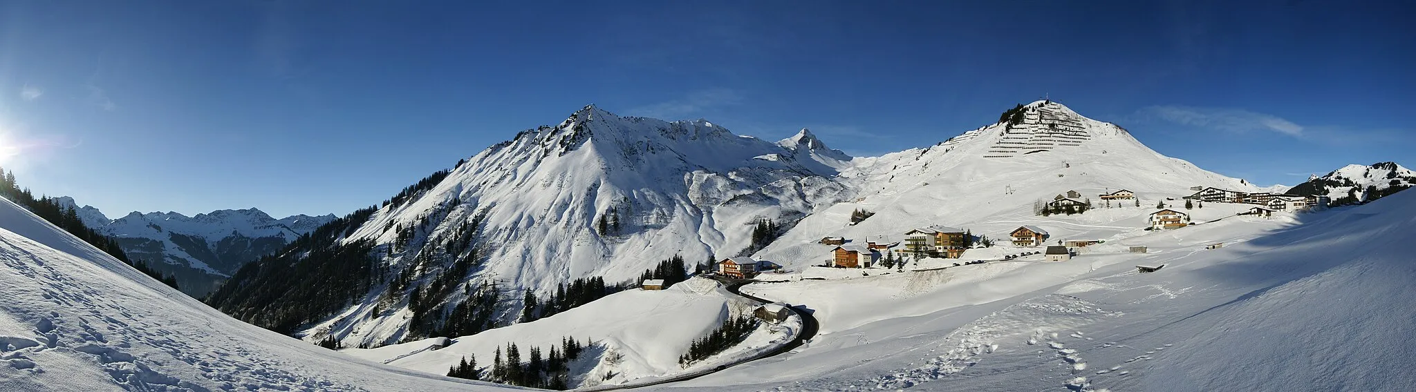 Photo showing: View from the foot of the Zafernhorn in the area of Fontanella-Faschina, from left to right the Bettlerspitze, Rote Wand (2,704 m), Formarin Rothorn, Glattmahd dem Gronggenkopf and the Kellaspitze. The centre of the picture shows the Sonnenköpfle. The prominent peak is the highest mountain of the Bregenzerwaldgebirge: the Glatthorn (2,134 m). The Hahnenkopf is blocked with avanlanche barriers. In the right edge of the photo you can see very small the Hochblanken, the Hohe Licht, the Damülser Mittagsspitze and finally the Elsenkopf, up to which leads the Ugalift. Over the col Faschina you can get to Damüls and into the Bregenzerwald. Over the street Faschina you drive to the left down to the Great Walsertal.