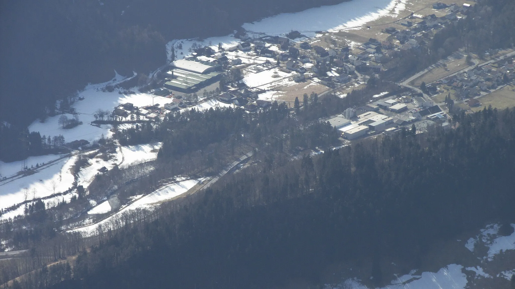 Photo showing: Blick von der Gamsfreiheit auf Stallehr mit den Hallen der Ganahl-Getränkefabrik, dem einzigen größeren Betrieb des Ortes. Das Dorf auf der Licht-Schatten-Grenze bekommt im Winter wegen der Davenna wenig Sonne. Rechts vorn über dem Wald ist Bings zu sehen.