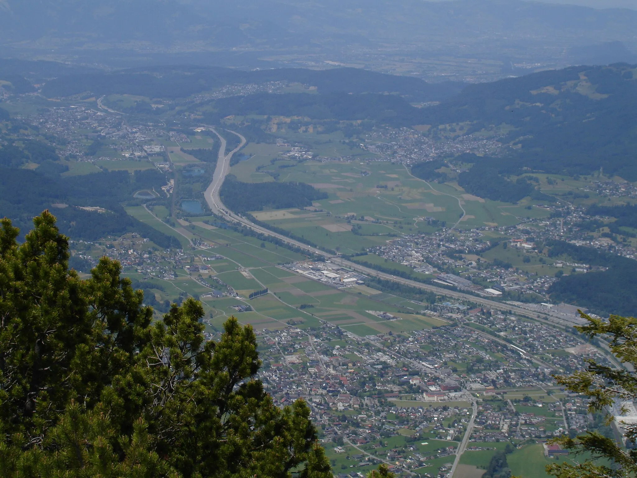 Photo showing: Blick vom Schwarzköpfle (ca. 1753 m) auf den etwa 1200 Meter tiefer liegenden Walgau und die ihn durchziehende und verlärmende A 14. Sie ist weitgehend neben der Ill angelegt. Im Hintergrund links verschwindet sie im Ambergtunnel. Die Bahnstrecke Lindau-Bludenz liegt links neben der Autobahn. Im Vordergrund ist Nenzing, links oben hinter den Seen Frastanz.