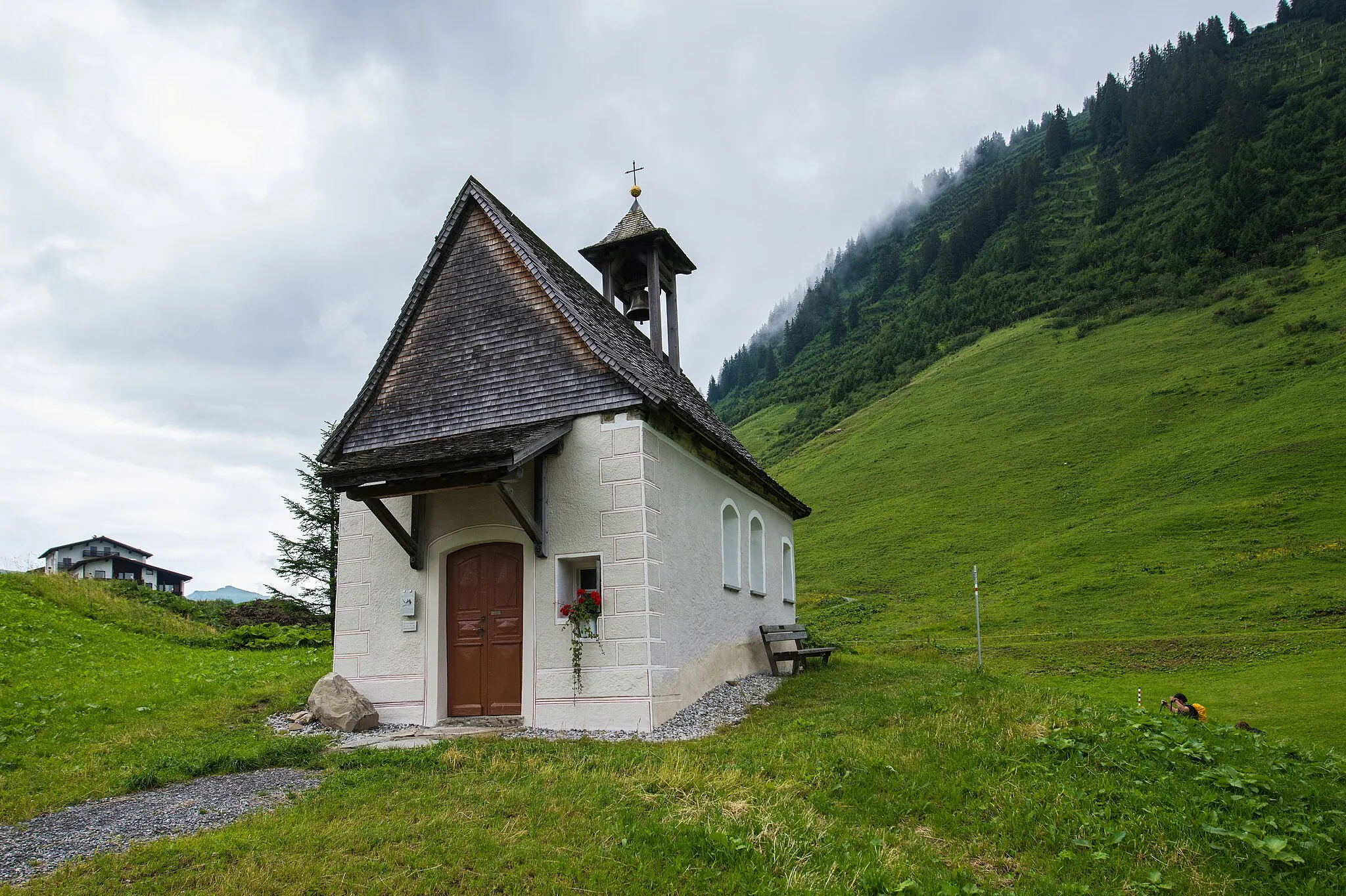 Photo showing: Kapelle Hl. Anna in Fontanella - Faschina. Der Steilhang im Hintergrund gehört zum Sonnenköpfle. aus dem DEHIO Vorarlberg 1983: Um 1700 als Stiftung von Dr. Josef Hartmann (später 1717-1720 Bürgermeister von Wien) erbaut. 1951/52 Restauriert. Rechteckbau mit Rundapsis unter gemeinsamem Satteldach und Glockendachreiter im Osten. Im Westen Vorzeichen mit Pultdach auf 2 Stützen, beschindelte Westgiebelfassade. Flachgedeckter Betraum mit Holzfelderdecke, eingezogener rundbogiger Chorbogen, Chorraum mit Wölbung. Barocker Altaraufbau um 1700, Altarbild hl. Anna mit Maria, Erstes 19. Jh., Figuren Hll. Maria mit Kind, Nikolaus, Andreas deponiert. Über dem Chorbogen Akanthuskartusche mit Relief Gottvater um 1700.