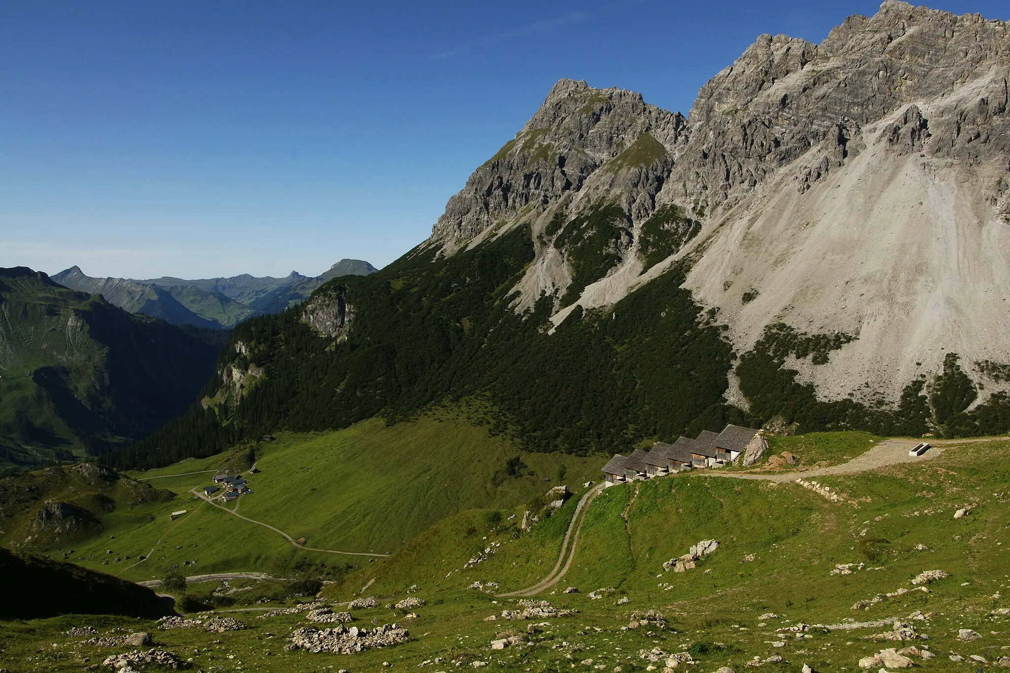 Photo showing: Blick auf das Vorsäss der Alpe Klesenza am Fusse der Roten Wand. Rechts die Spitzegga Alpe im Hintergrund erhebt sich die 2.272 Meter hohe Bettlerspitze sowie die Gadnerköpfe 2.271m im Gadnergschröf. Im Gebirgszug am Horizont erkennt man die markante Damülser Mittagsspitze 2.097m.