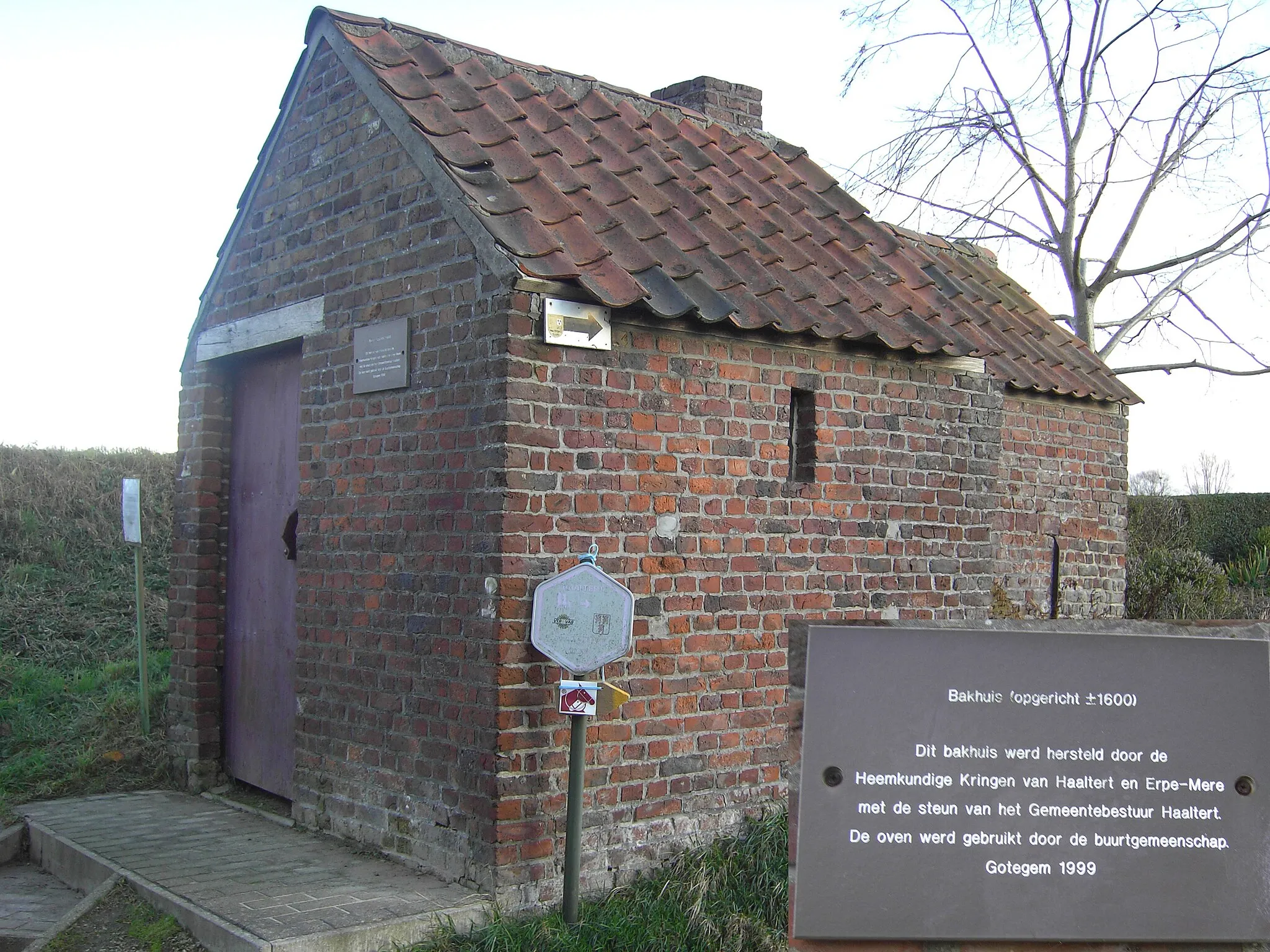 Photo showing: Bakoven in Gotegemstraat - grens Haaltert en Erpe-Mere - Oost-Vlaanderen - België
Het markante gebouwtje is eigenlijk een bakoven die zou dateren van
omstreeks 1600. Tot na WO II werd de oven beurtelings door drie
families in gebruik genomen die per bakbeurt ongeveer 40 broden
produceerden. Elke familie bezat een sleutel en diende zelf voor hout
te zorgen. De oven werd steeds minder gebruikt en werd min of meer
verwaarloosd, tot in 1999 de heemkundige kringen van Haaltert en
Erpe-Mere en het Haalterts gemeentebestuur voor een grondige restauratie zorgden. Een rustbank en picknicktafel, geplaatst door de
VTB-afdeling Haaltert, maken van dit plekje een uitgelezen rustpunt
om te genieten van de stilte van Den Dotter. De oven is nu niet meer
courant in gebruik, maar bij speciale gelegenheden worden nog

‘ovenkoeken’ gebakken.