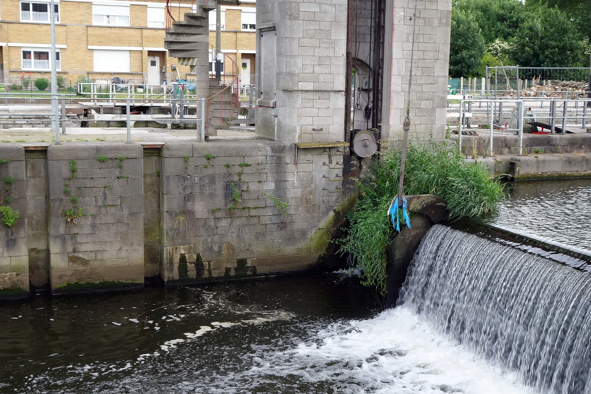 Photo showing: Hérinnes  — Barrage sur la rive gauche de l'Escaut.
en service de 1922 à 2018.
Fonction de clapet et de  vanne murale . l'eau passe au dessus et en dessous.
Lorsque le débit de l'Escaut est important, on relève l'ensemble (d'où les cables et la structure pont -non- roulant  ; dès lors la  plus grande partie du flue s'écoule en dessous de la structure  tout comme l'eau passerait sous une vanne d'eau.

Si faible débit du fleuve, les quelques M³ changent de bief par la partie bec du dessus.