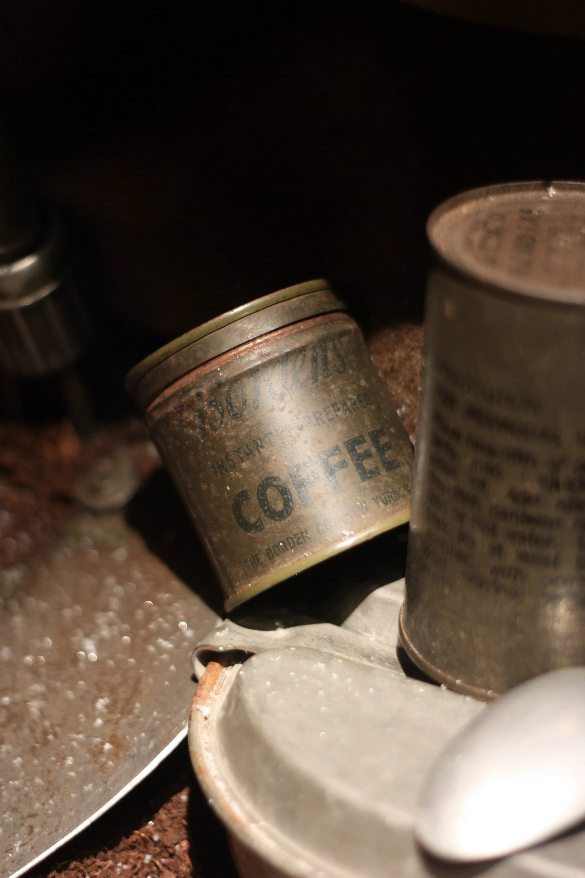 Photo showing: Close-up photo of a collection of misc. WW2 militaria: historical weapons, uniforms, military equipment, everyday items, etc. on display at the Baugnez 44 Historical Center, a WW2 museum in Baugnez les Malmedy in Belgium focusing on the Battle of the Bulge (the Ardennes Counteroffensive) from 16 December 1944 to 25 January 1945 and Malmedy massacre on 17 December 1944. Bordens instant coffee in tin box can etc.