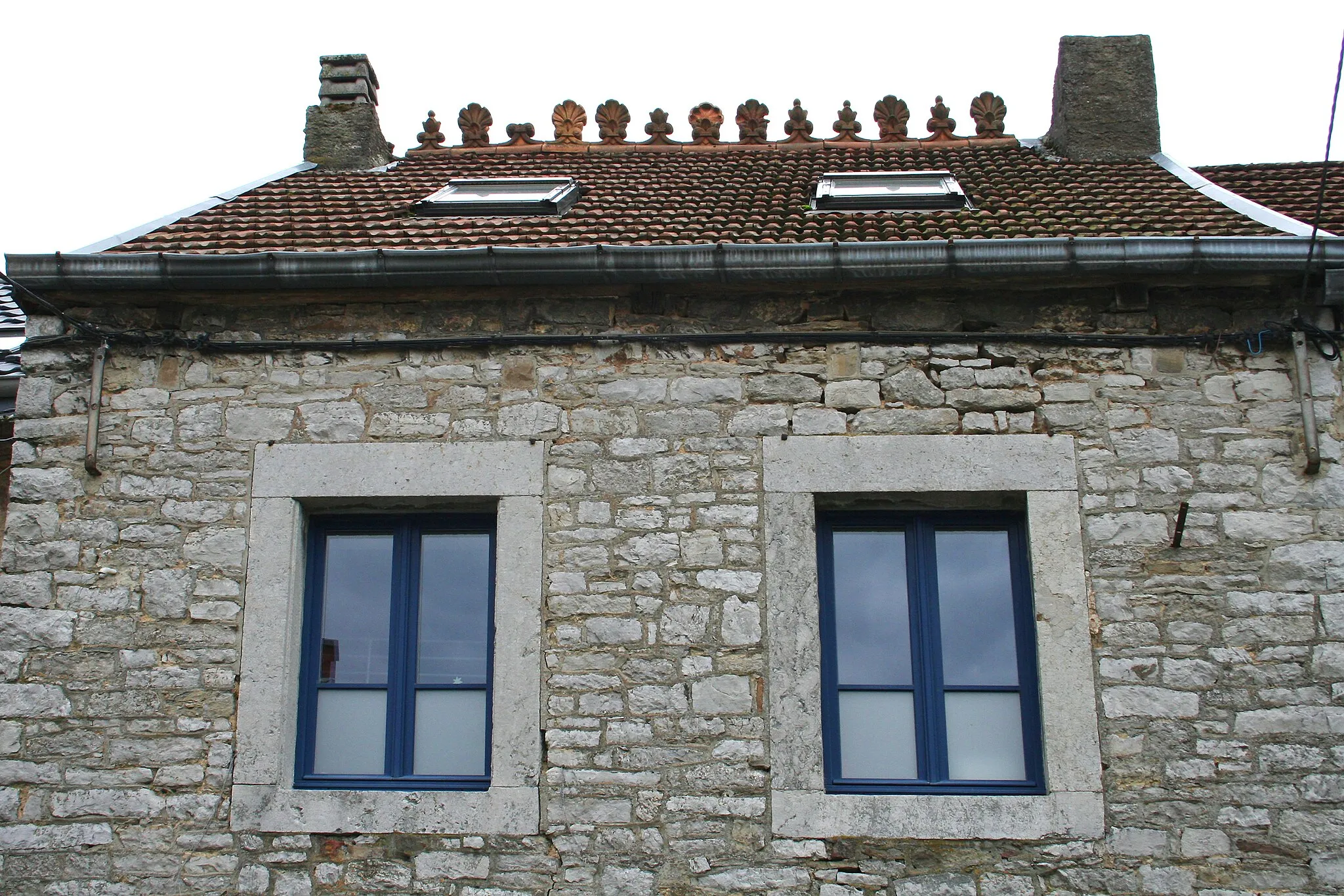 Photo showing: Tuiles faitières à motifs décoratifs couvrant le faîtage de la toiture d'une maison à Deigné (Belgique).