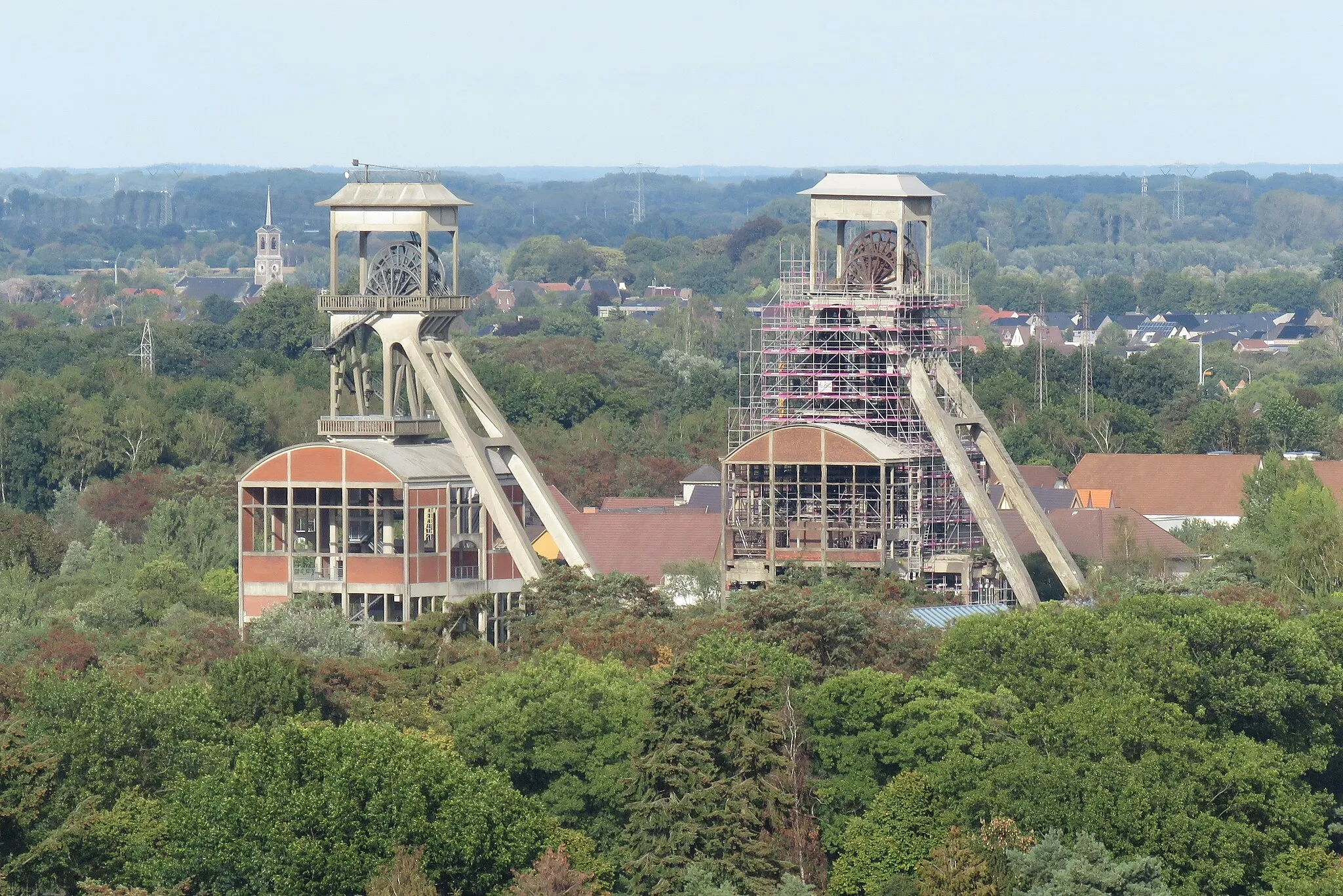 Photo showing: Schachtbokken van de vroegere koolmijn van Eisden (Maasmechelen) vanuit de toren van de mijnkathedraal van Eisden. Met de kerktoren van Stokkem op de achtergrond.