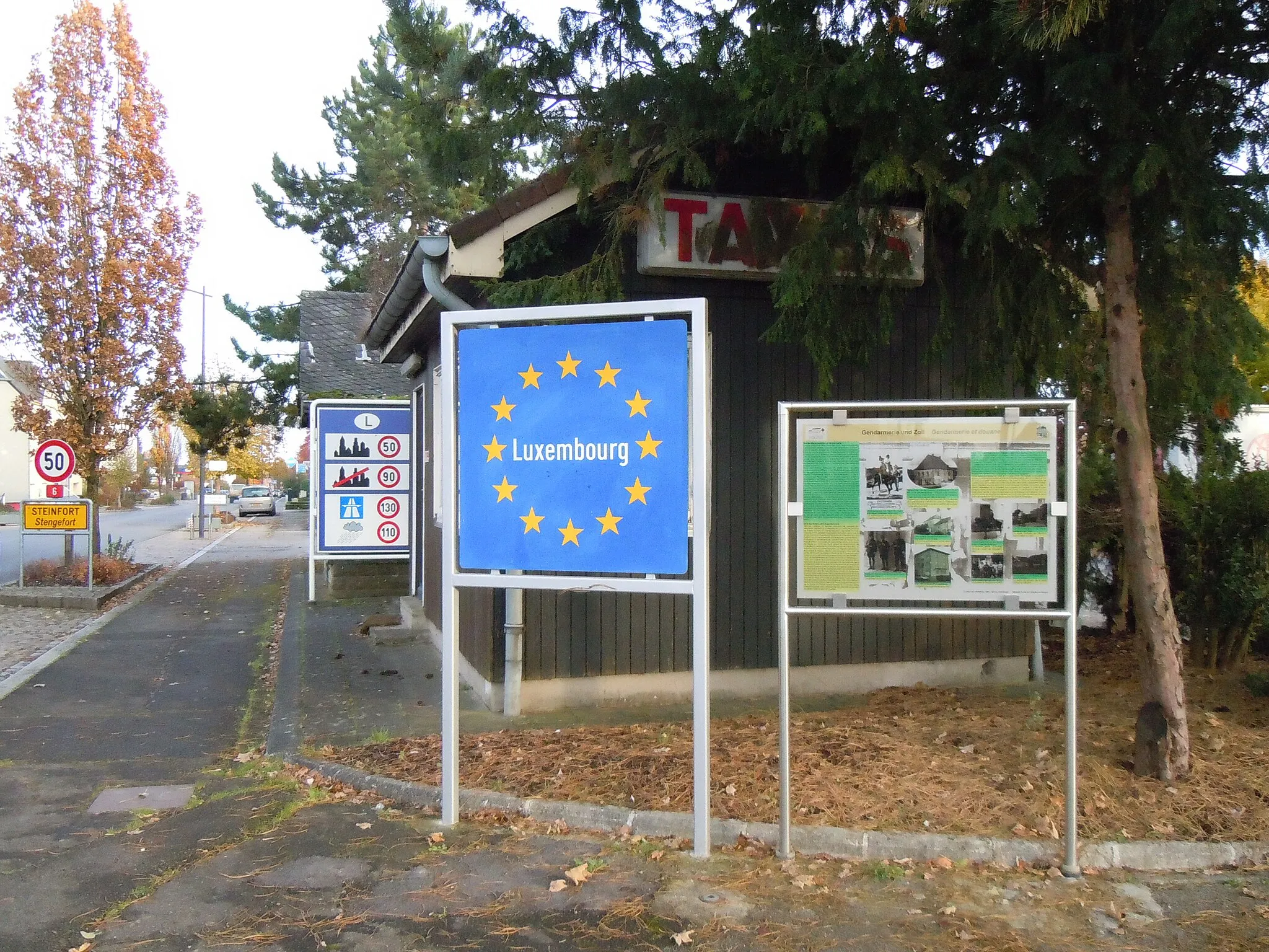 Photo showing: Customs-house, road signs and information board at the Belgian border in Steinfort, Luxembourg.