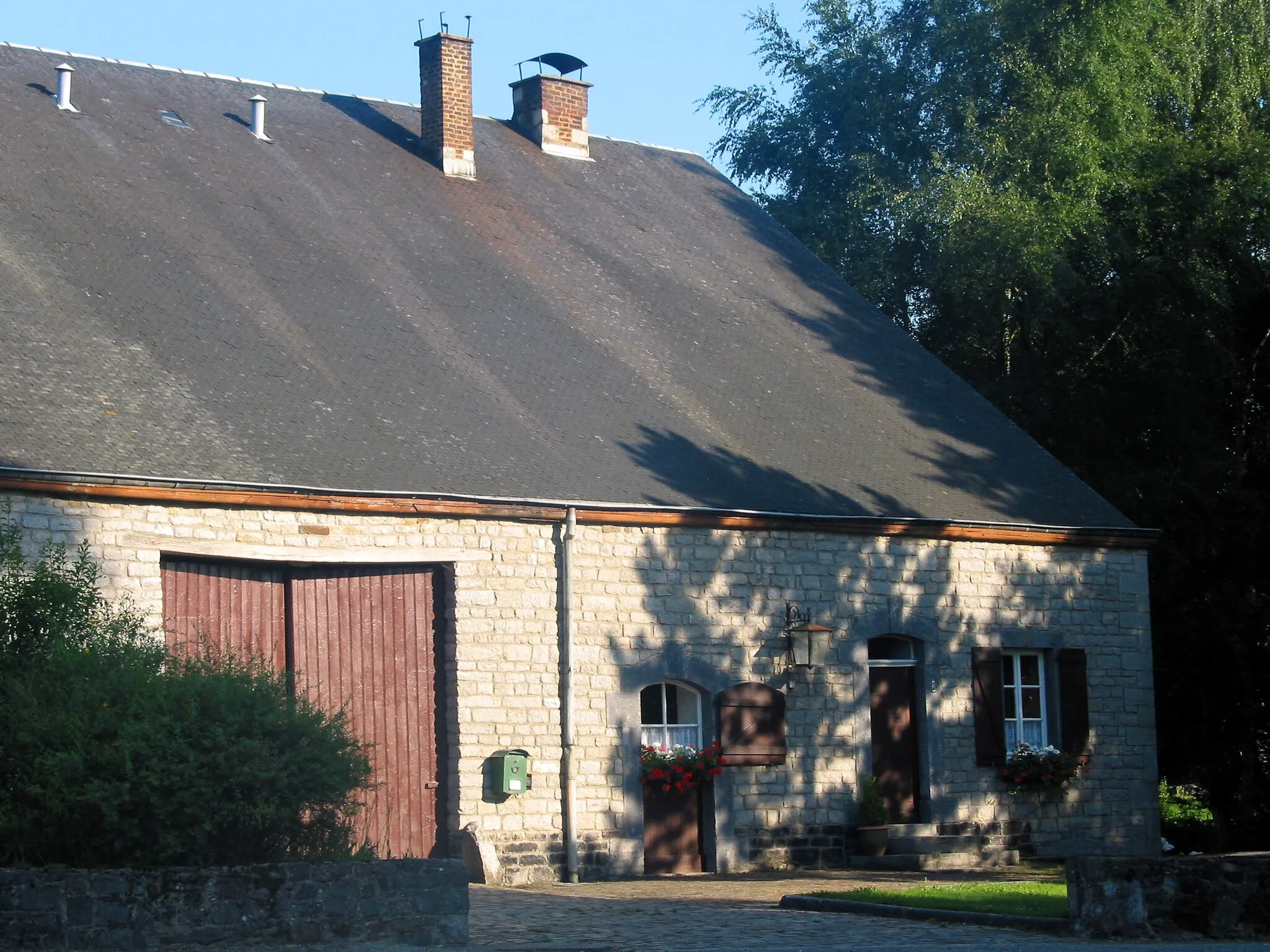 Photo showing: Ambly (Belgium), typical old farm with his roof covered with slades of grey schist and his façade builded of grey calcareous carry stones (XIXth century).