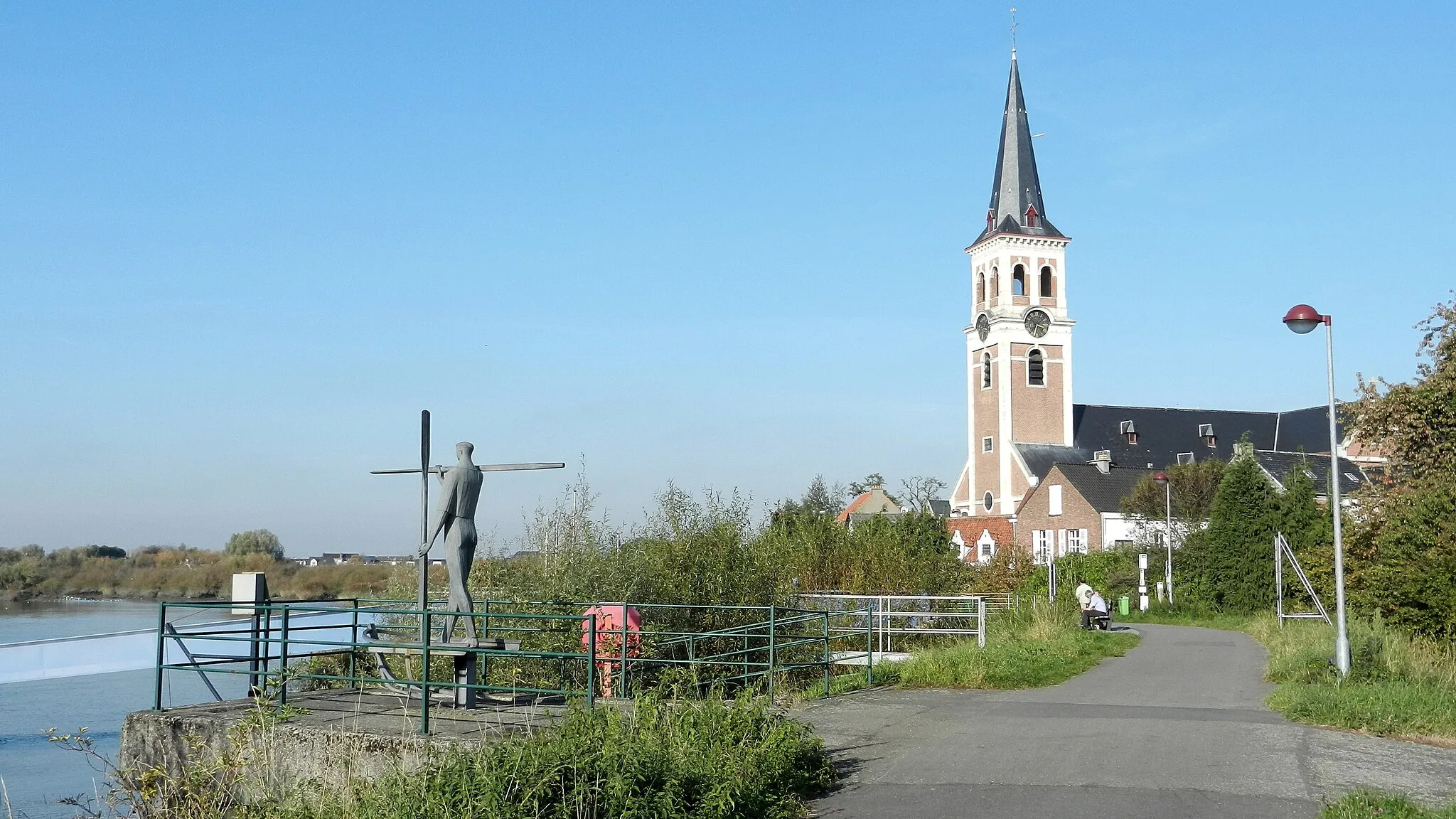 Photo showing: De Sint-Amanduskerk en het metalen beeldhouwwerk ‘De Veerman’  door Marc Macken, geïnspireerd door het gedicht ‘Le Passeur d’Eau’ van Emile Verhaeren (die even verderop begraven ligt).

The Saint Amand church and the metal sculpture "The Ferryman" by Marc Macken, inspired by the poem "Le Passeur d'Eau" by Emile Verhaeren (who is buried a bit further).