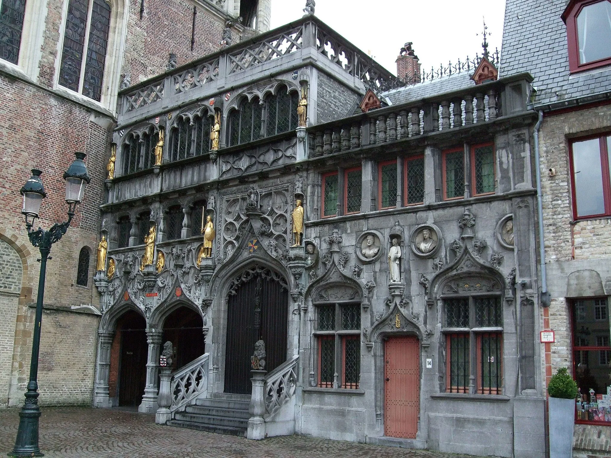 Photo showing: The basilica of the Holy Blood was built between 1134 and 1157 by the Count Diederik van de Elzas. Ever since it was built it was a double church, the ground floor was able to maintain its Roman character, while the top church got deteriorated. It wasn't untill the 19th century that restaurations began. The original name of the chapel was Saint Baselius Chapel. According to the legend Diederik van de Elzas would have brought the Holy Blood of Jesus Christ to Bruges. The relic of the Holy Blood is kept in the chapel of the church ever since the 13th century. The relic is probably from Constantinople, from were it was brought to Bruges. Count Baldwin IX was partly responsible. .

Location for the film In Bruges (2007).