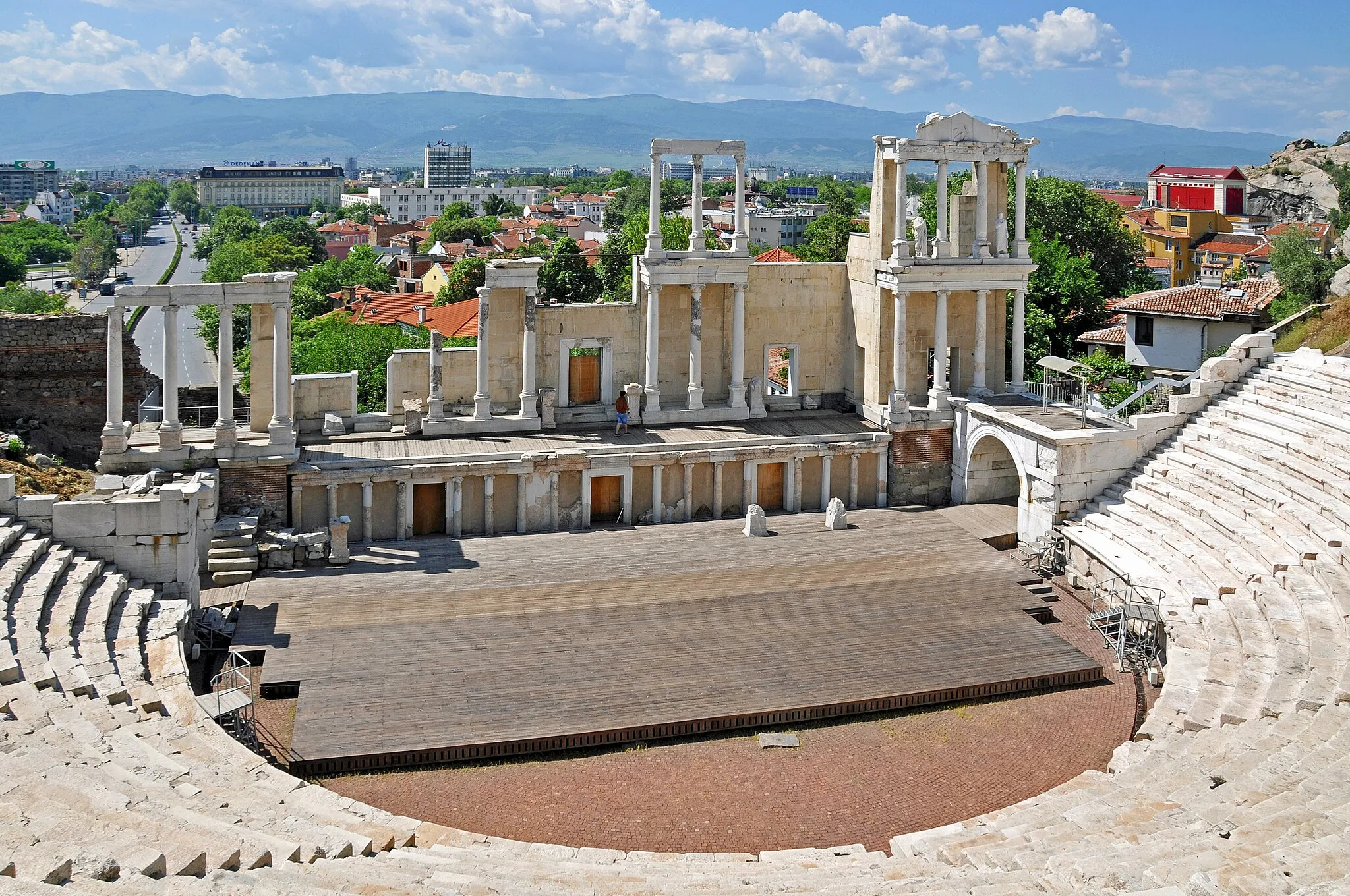 Photo showing: The Roman theatre of Philippopolis is a semi-circle with an outer diameter of 82m (269ft). The stage building (the skene), is situated south of the orchestra and has 3 floors. The stage area (proskenion) is 3.16m (10.4ft) high and its facade, which is facing the orchestra, is decorated with an Ionic marble colonnade with triangular pediments.
According to a builders’ inscription, discovered on the frieze-architrave of the eastern proskenion, the construction of the theatre dates back to the time of Emperor Trajan.
Built with 7,000 seats, each section had the names of the city quarters engraved on the benches so the citizens at the time knew where they were to sit.
The theatre was damaged in the 5th century AD by Attila the Hun.
The theatre was found again in the 1970s due to a landslide, this started a major archeological excavation.

My photos are FREE for anyone to use, just give me credit and it would be nice if you let me know, thanks - NONE OF MY PICTURES ARE HDR.