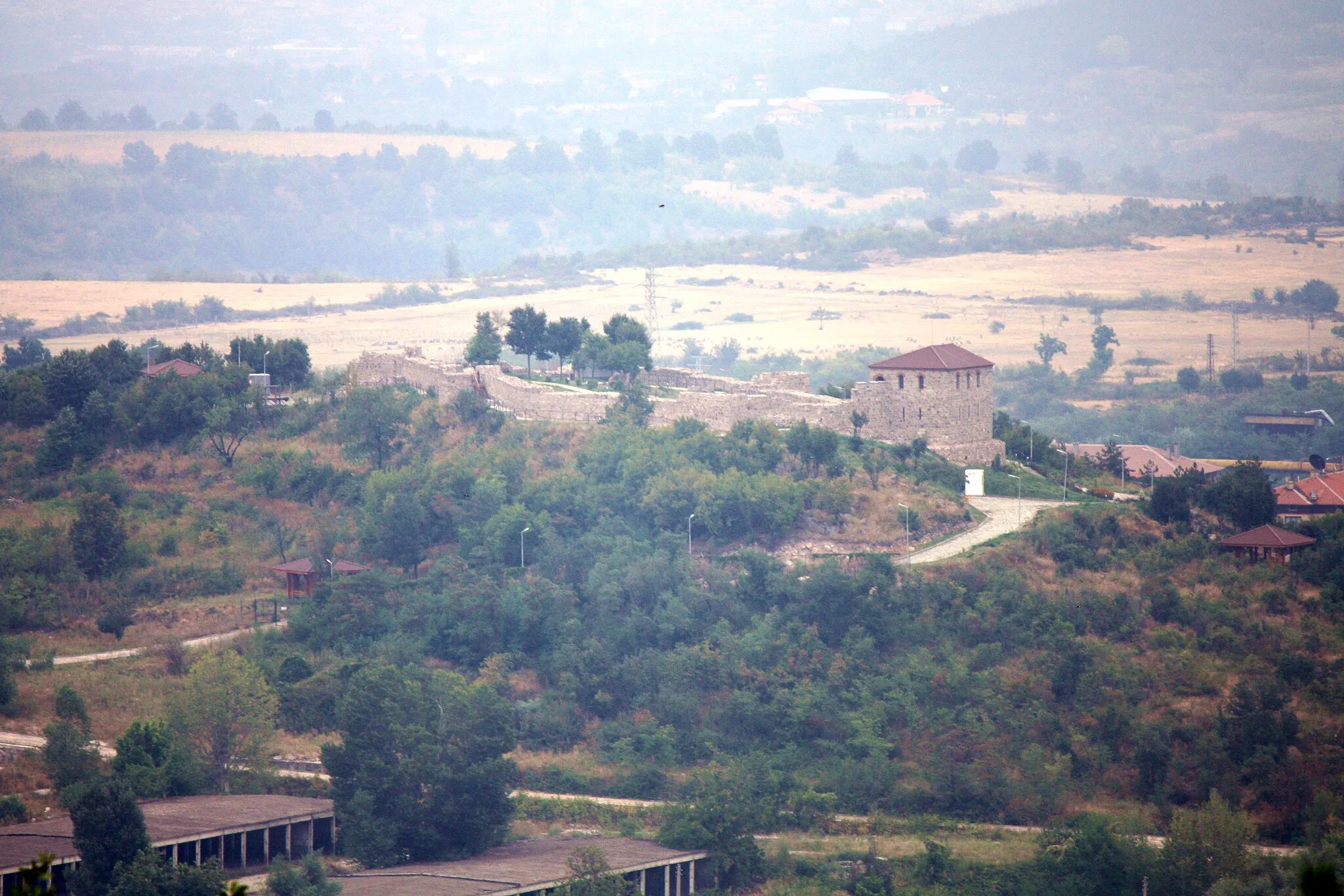 Photo showing: Blick auf den Hügel "Sweta Petka" mit der Festung "Peristera Fortress", aufgenommen im August 2015 vom Osthang des Berges "Turska Glava" (Турска глава) auf rund 600 m über NN. Der Berg befindet sich westlich der Stadt. Im Vordergrund die Baracken des ehemaligen Militärstützpunktes in Peschtera. IMG 9193