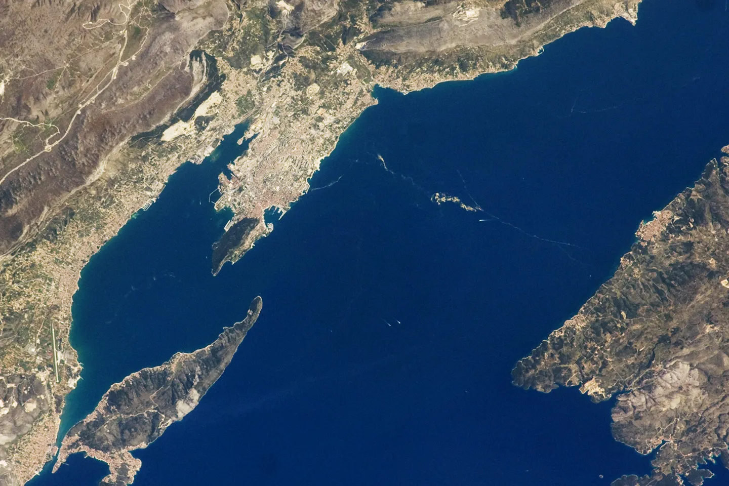 Photo showing: In this image, a thin zone of disturbed water (tan patches) marking a water boundary appears in the Adriatic Sea between Split and the island of Brač. It may be a plankton bloom or a line of convergence between water masses, which creates rougher water.