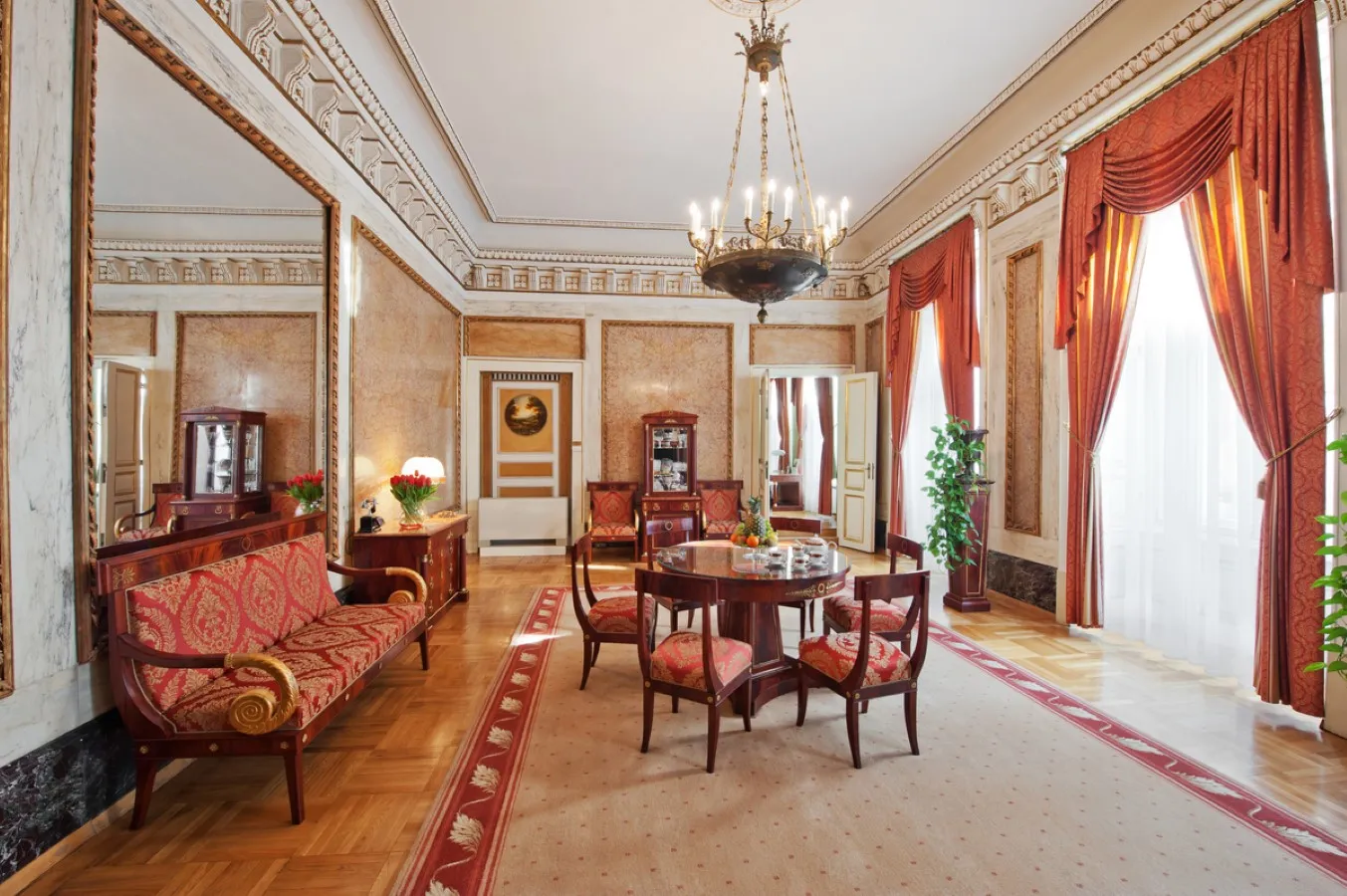 Photo showing: The walls of the most beautiful and largest hotel suite – the Marble Suite – with an area of about 100 m2 , are adorned with thick layers of unique pink Chęcin marble bordered by gilded frames subtly adorned with acanthus leaves. The smart door curtains, the carpets and Empire style furniture selected with excellent taste add extra warmth to the marble interior. The luxury design is complemented by crystal mirrors, refined stucco, an original Empire chandelier, and historical details.