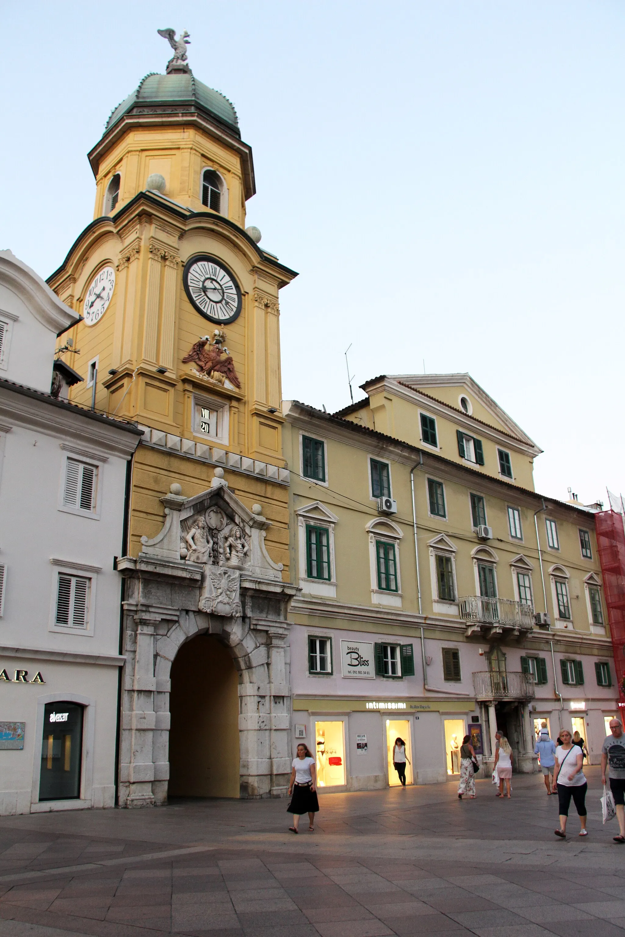 Photo showing: Luka - Korzo

City Clock Tower was built in the Middle Ages, probably on the foundations of the Late Antique littoral town gates. Some baroque phases of its construction can be seen on the lower part of the front of the Tower, which are characterised by a richly decorated portal, an imperial coat of arms carved out of stone and a relief of the Austrian emperors Leopold and Charles VI.
